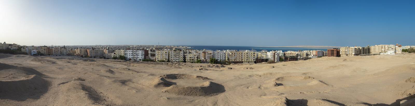 Panorama of large coastal town city with sea view on edge of arid harsh desert landscape