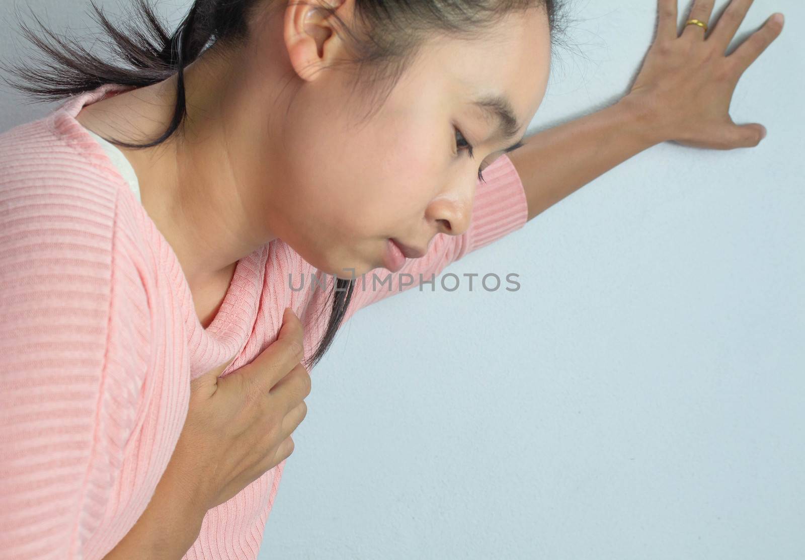 Asian young woman suffering from chest pain caused by heart disease. by TEERASAK