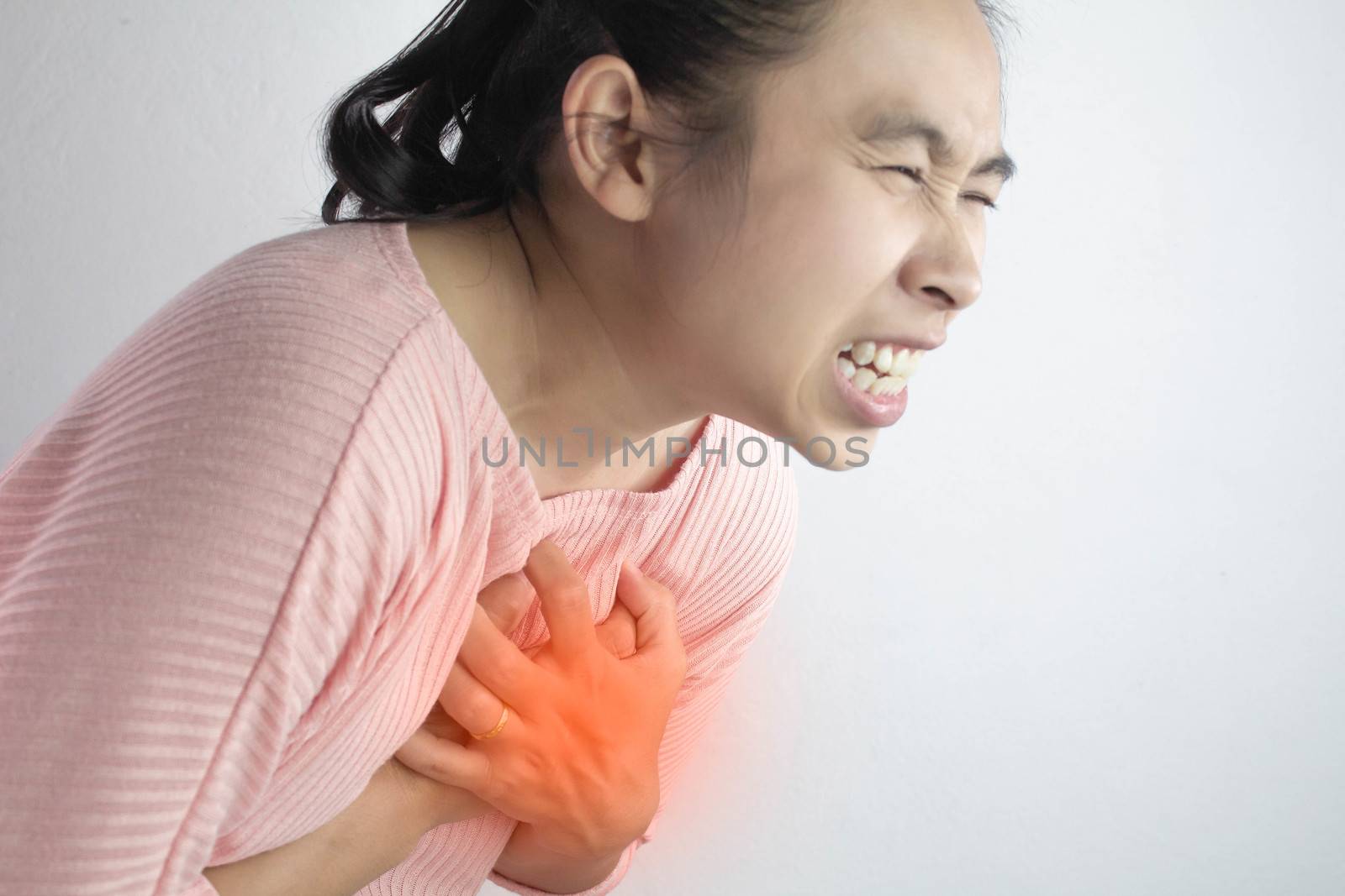 Asian young woman suffering from chest pain caused by heart disease.