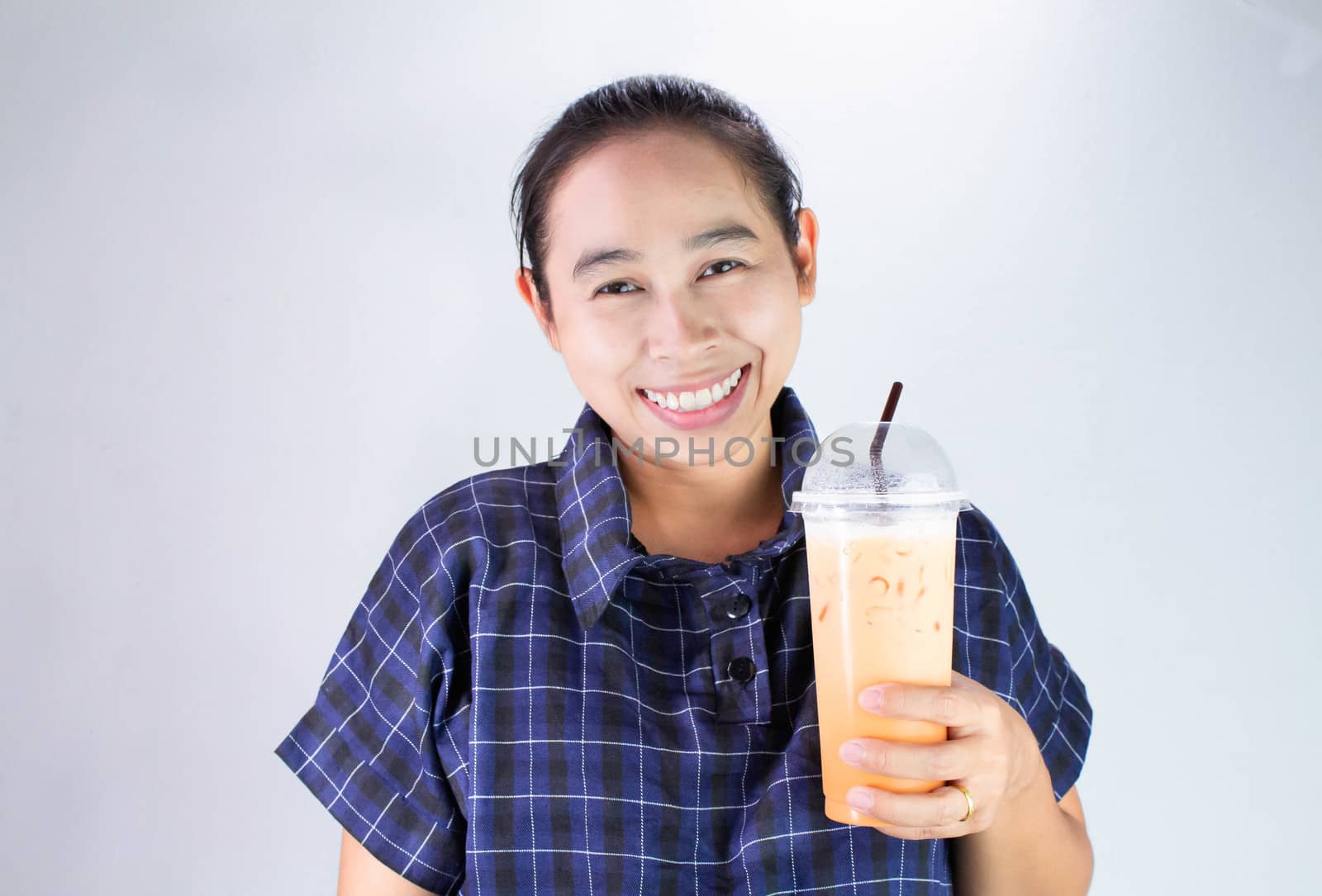 Happy Asian young woman is drinking Thai tea with milk. Popular beverage in Asia. by TEERASAK