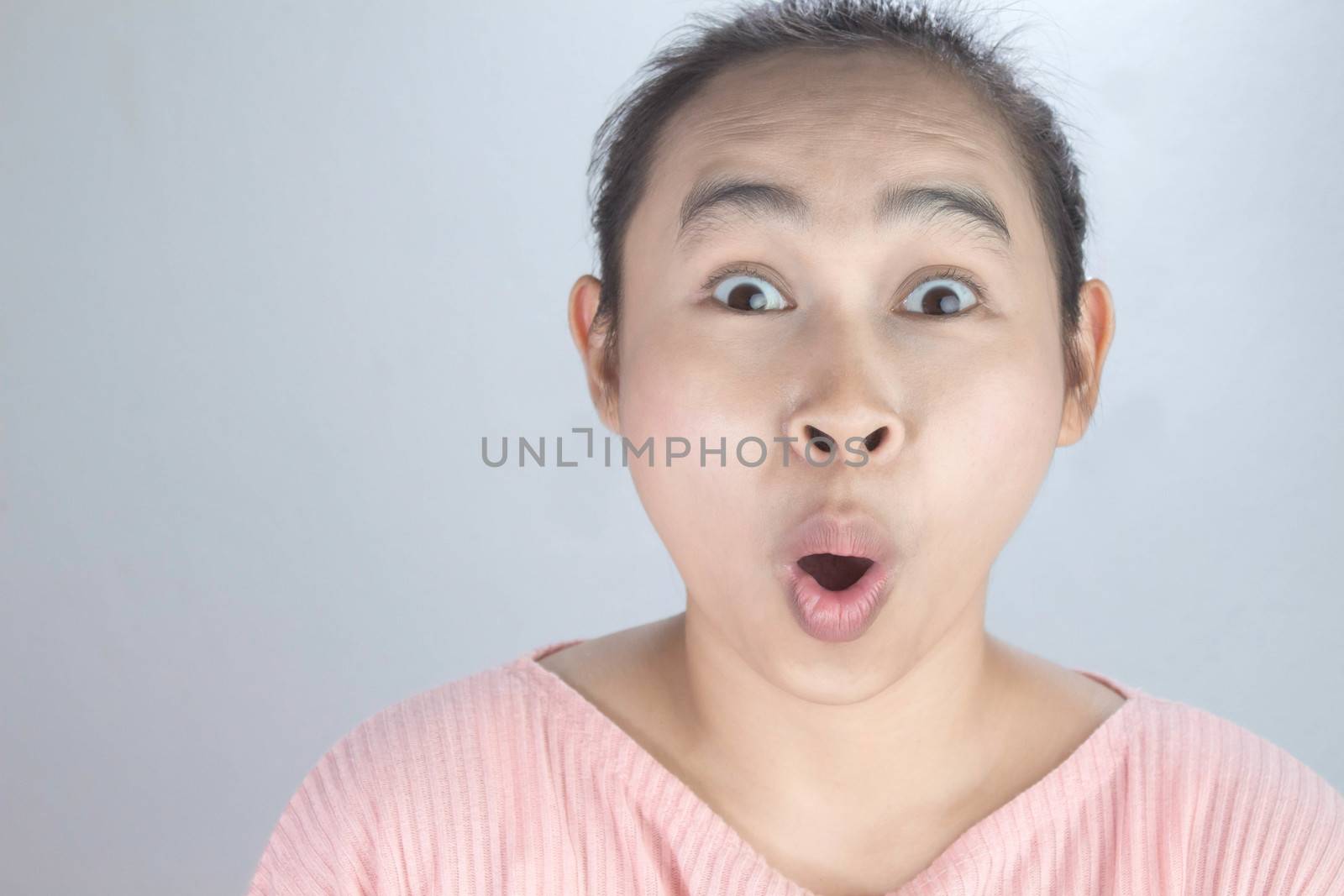 Portrait wow and surprised face of Asian young woman in pink shirt on grey background. by TEERASAK