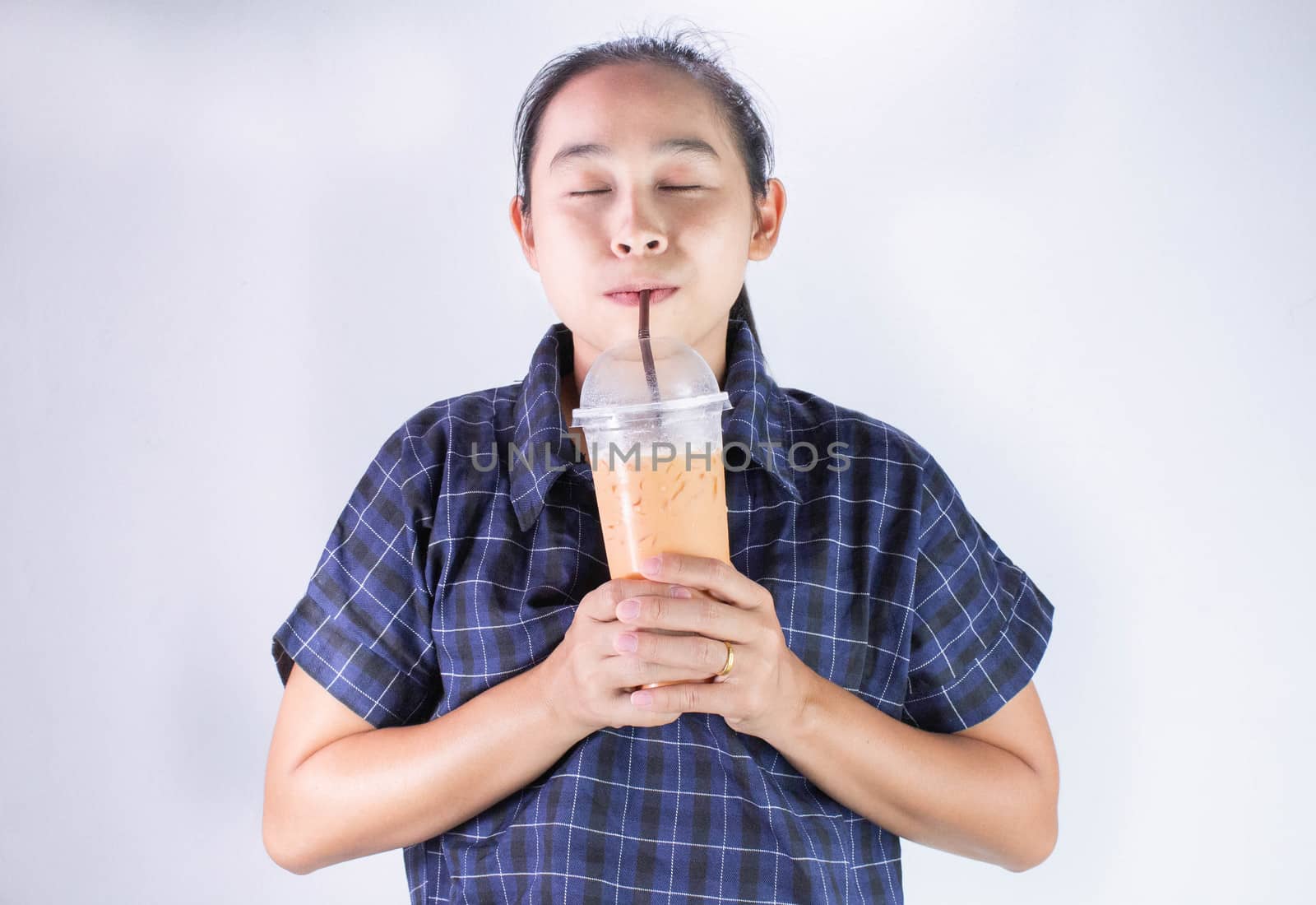 Happy Asian young woman is drinking Thai tea with milk. Popular beverage in Asia.