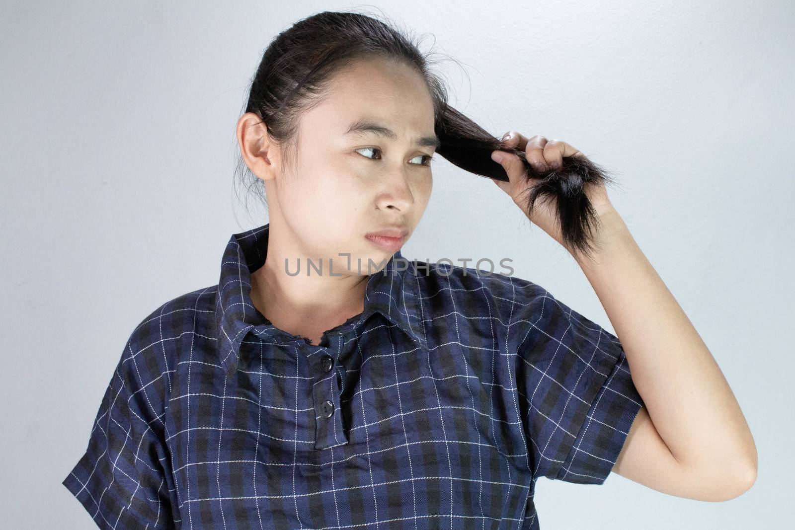 Portrait of Asian young woman with ends of long hair care problems; dry hair and split ends. Treatment and Hair care concept. by TEERASAK