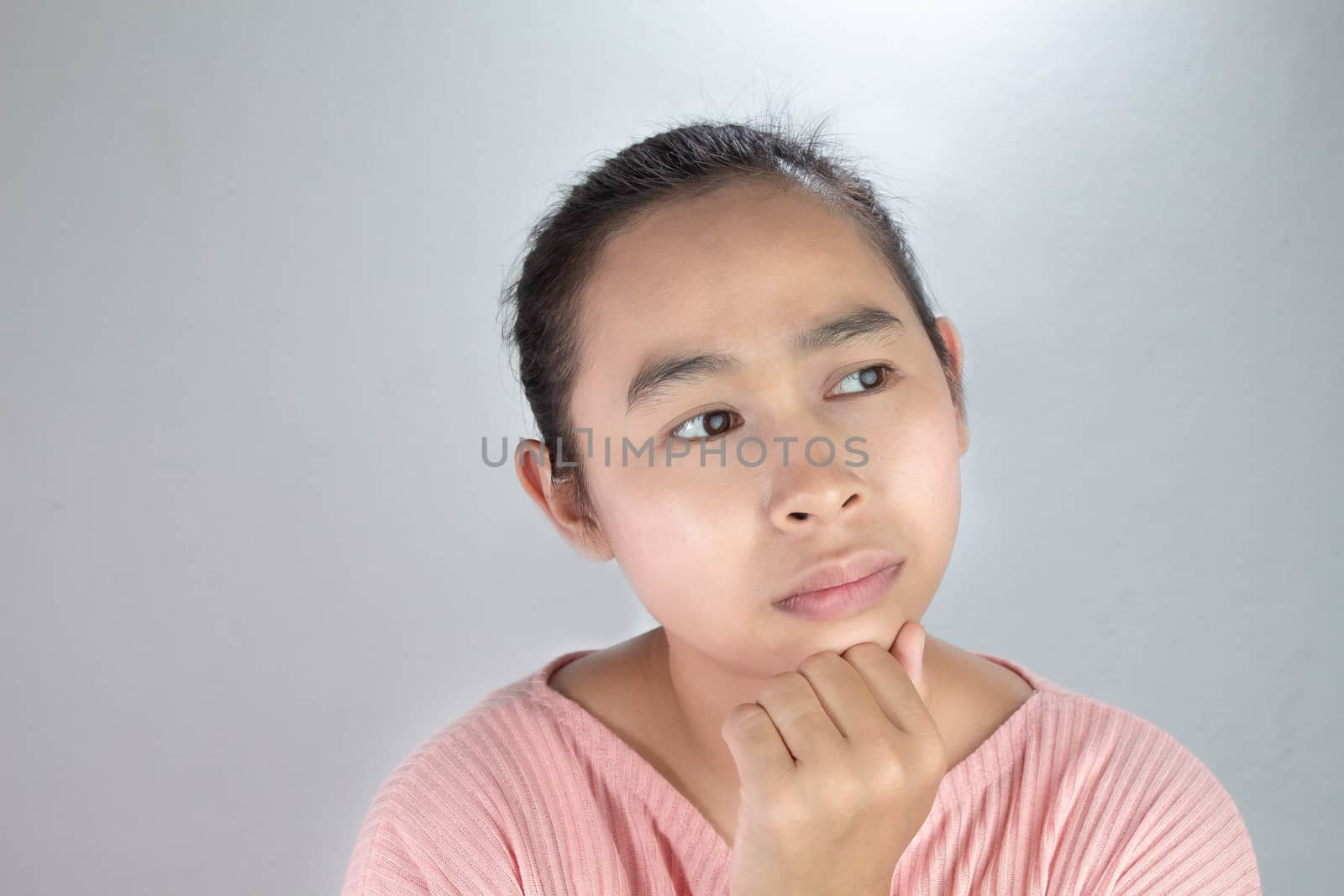 Portrait Thinking face of Asian young woman in pink shirt with hand on chin on grey background.