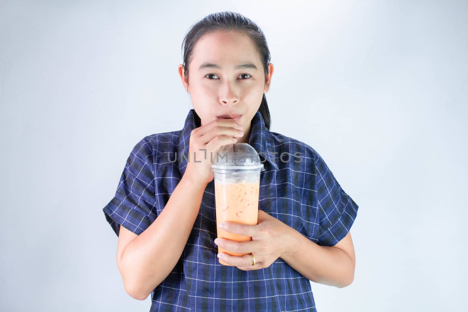 Happy Asian young woman is drinking Thai tea with milk. Popular beverage in Asia. by TEERASAK