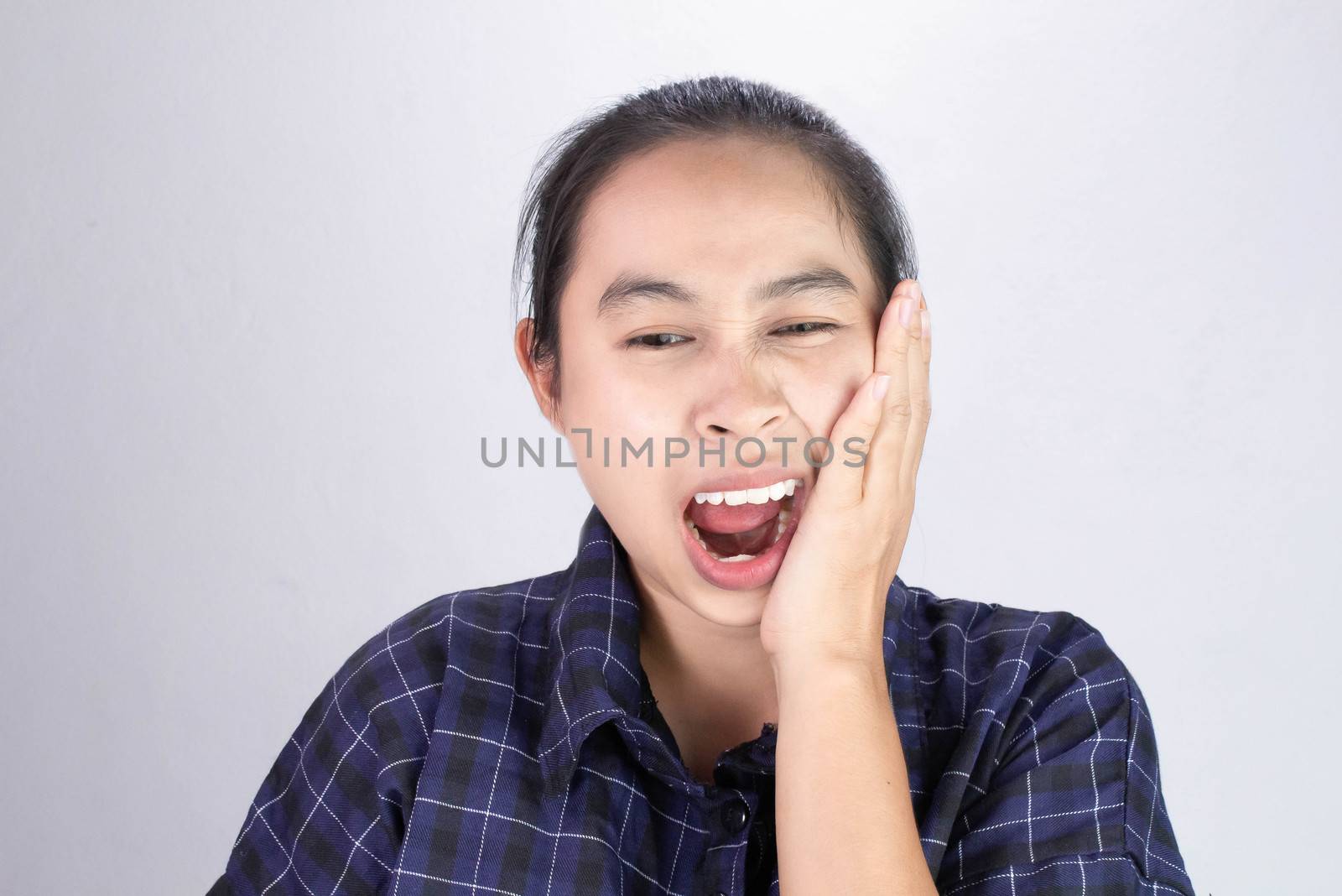 Asian woman touching cheek with hand because she is suffering of toothache. Dental care and health concept.