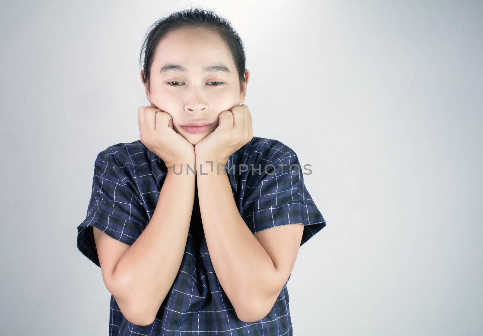 Portrait of young woman looking bored and put hands on chin isolated on a grey background. by TEERASAK