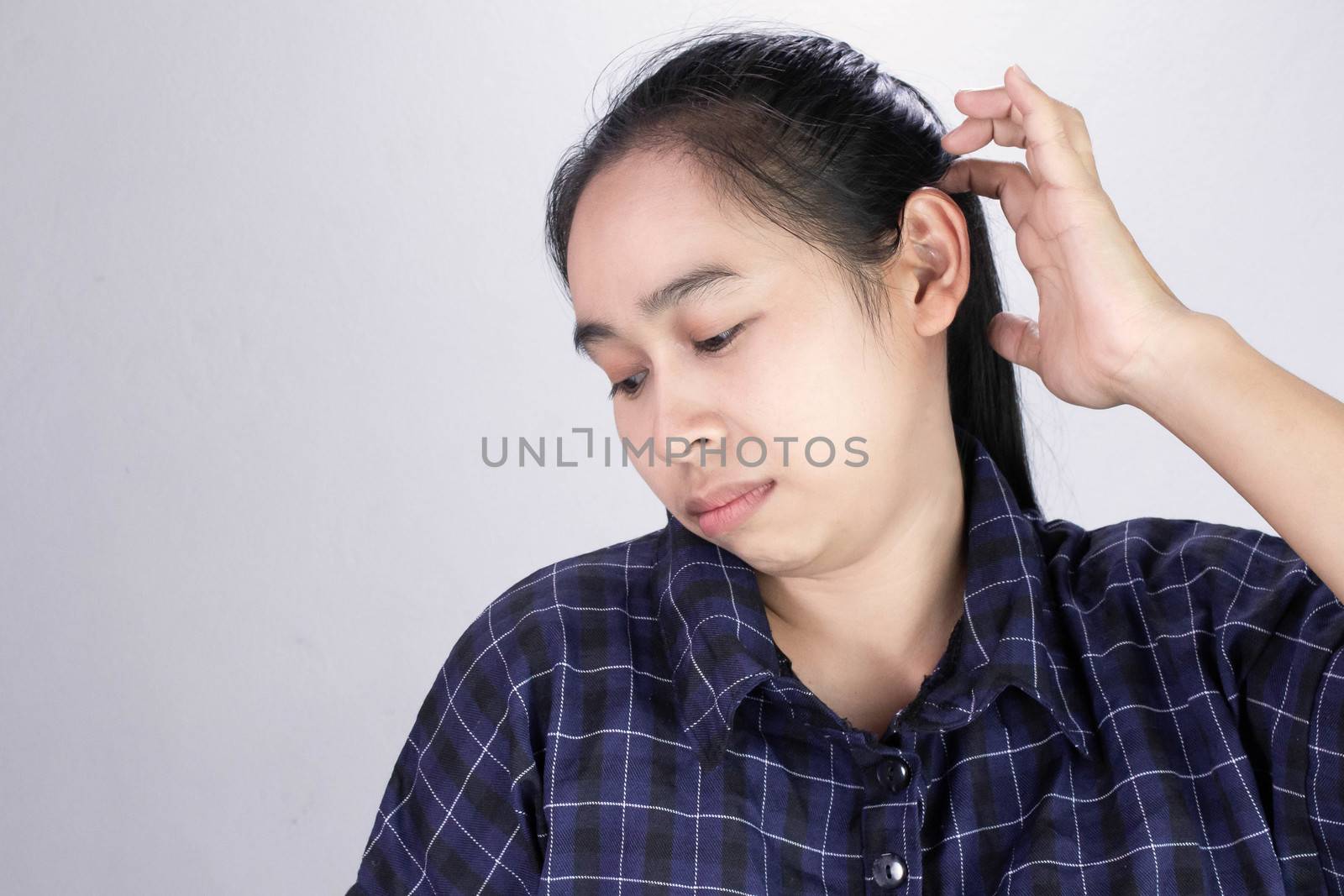 Asian young woman has itchy on her scalp isolated on grey background. Concept of scalp and hair care.
