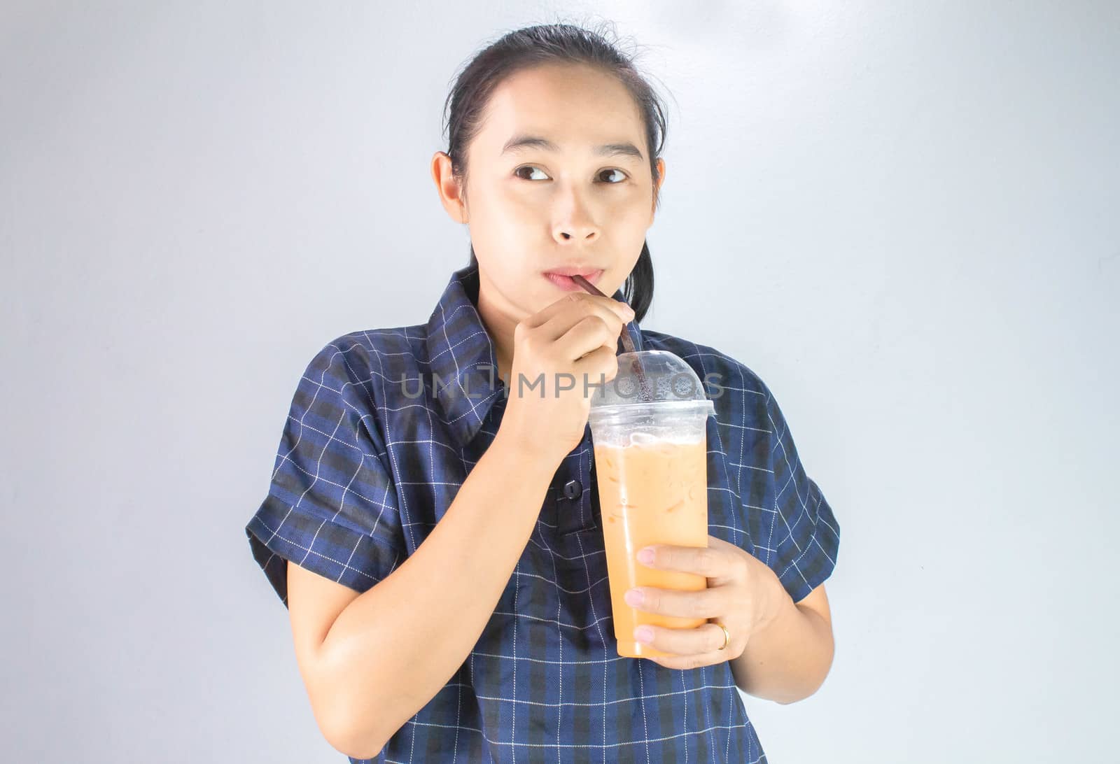 Happy Asian young woman is drinking Thai tea with milk. Popular beverage in Asia. by TEERASAK