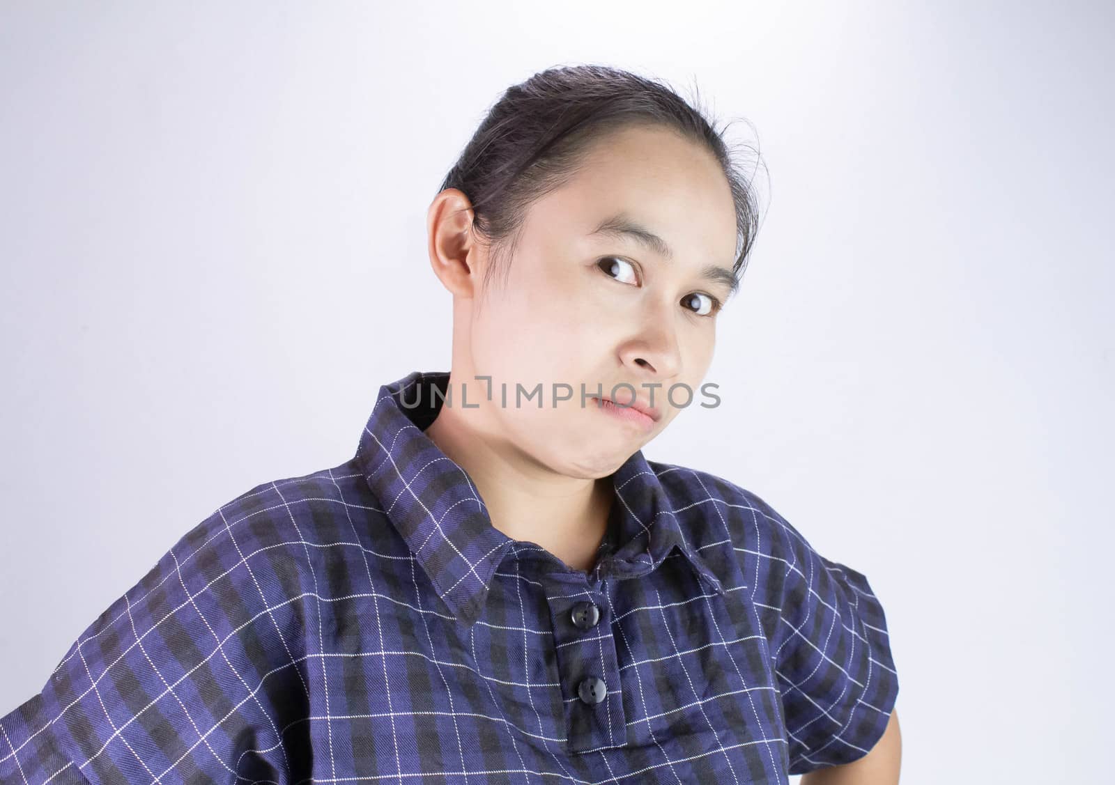 Close-up Angry face of Asian young woman in blue shirt with look to the camera. by TEERASAK