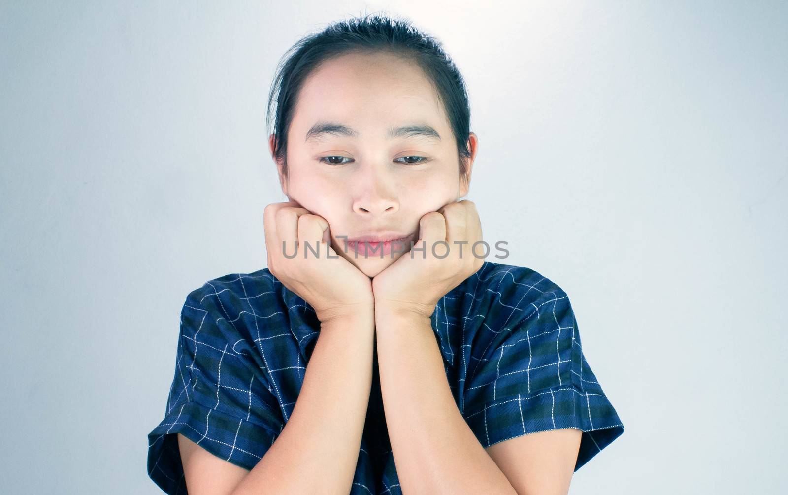 Portrait of young woman looking bored and put hands on chin isolated on a grey background.