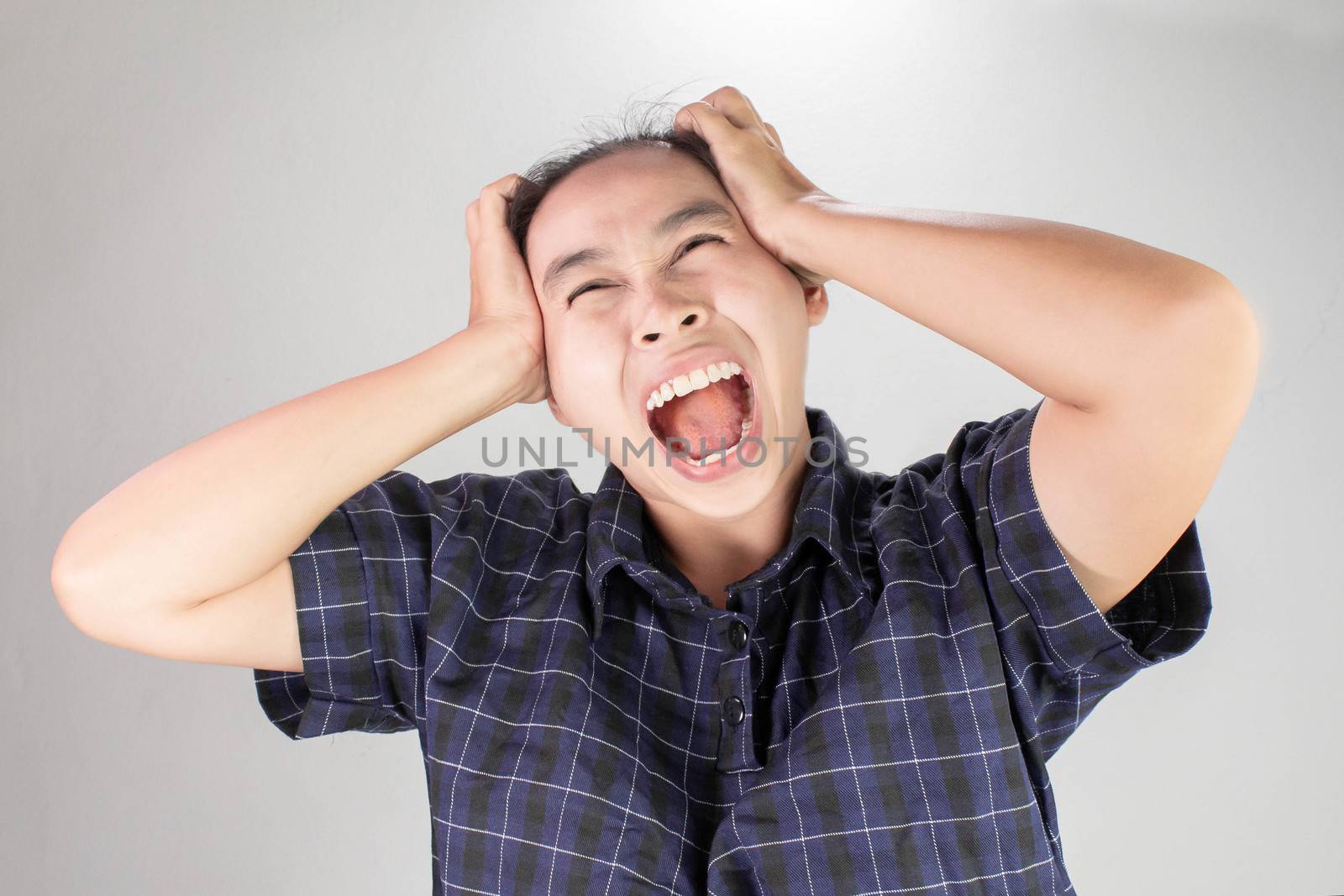 Portrait of a stressed woman holding head in hands and yells loudly. by TEERASAK