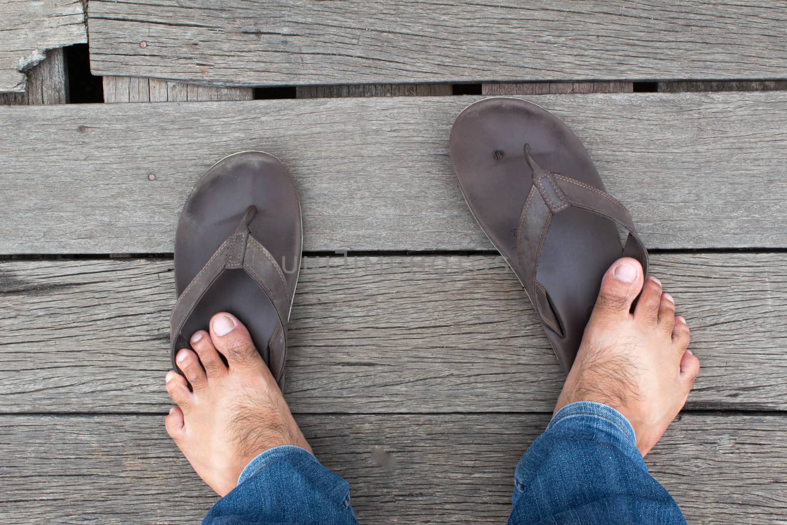 Bare feet of Asian men standing on wooden floor. Broken shoes. by TEERASAK