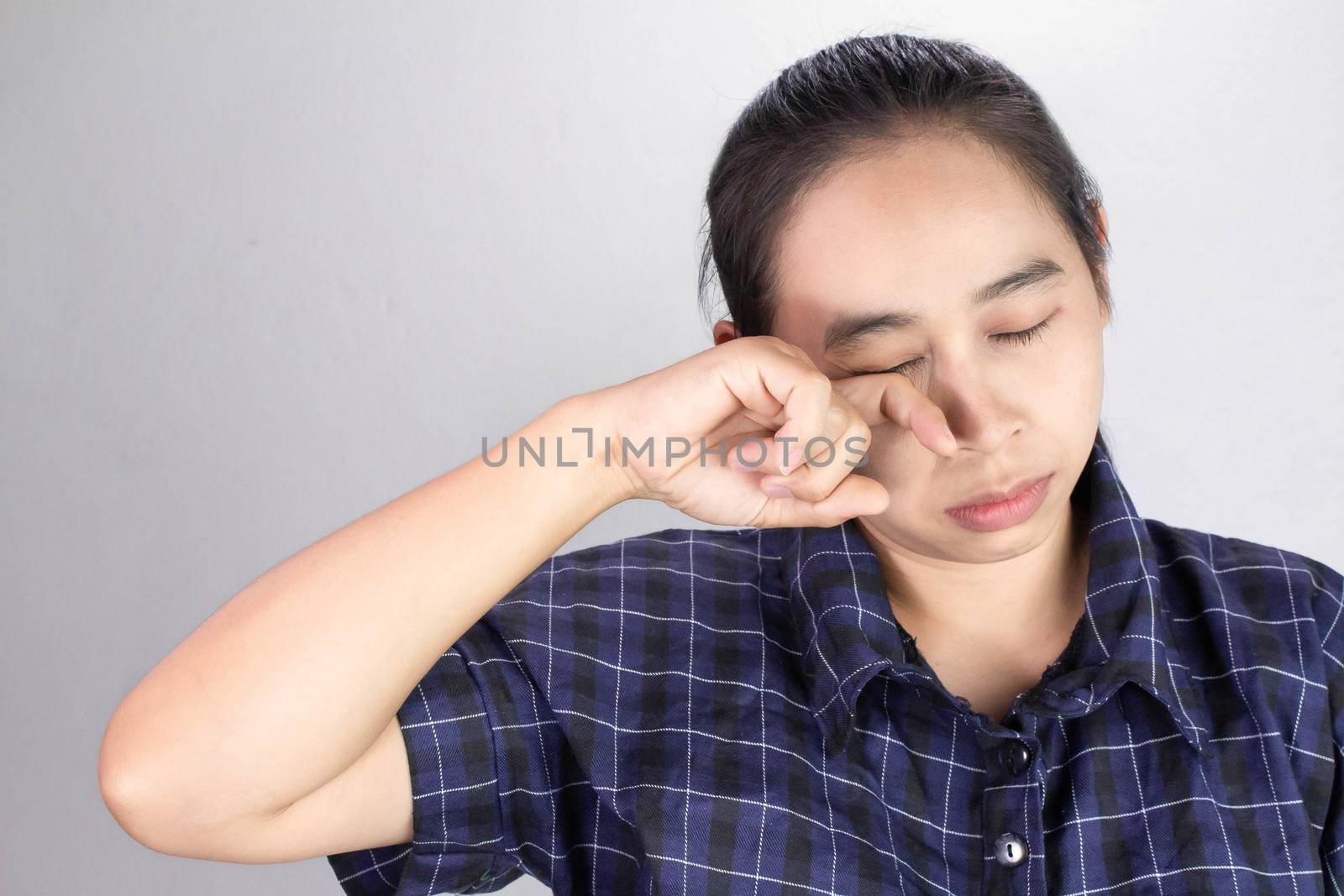 Asian young woman suffering from irritated eye, allergic or itching from dust. Optical health care concept. by TEERASAK