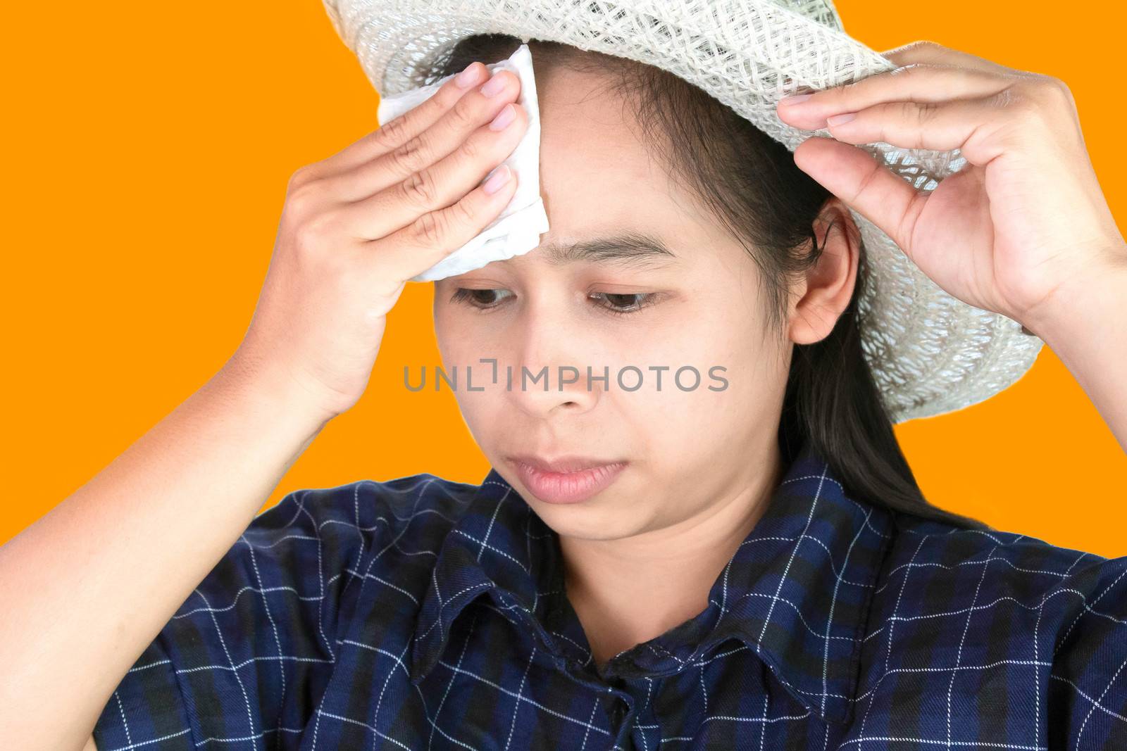 Asian young woman uses a tissue to wiped the sweat on her forehead on a hot day. by TEERASAK