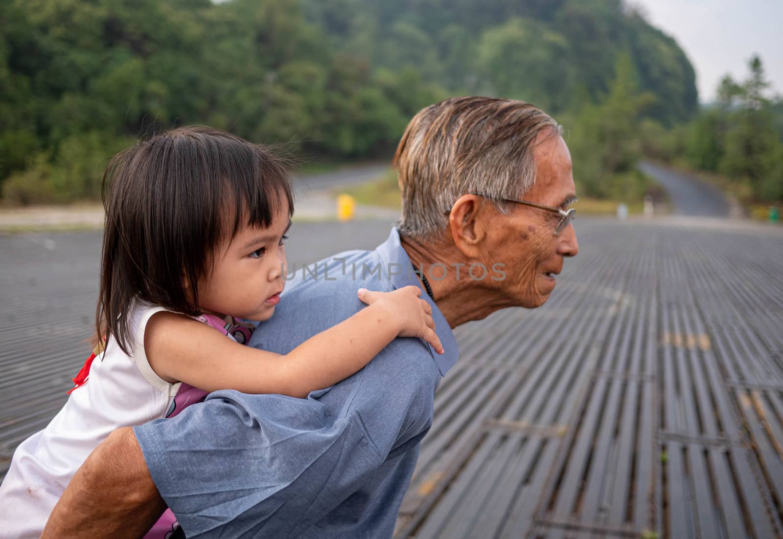 Granddaughter riding behind Grandfather and looking at beautiful scenery at Inthanon viewpoint, Chiang Mai,Thailand.