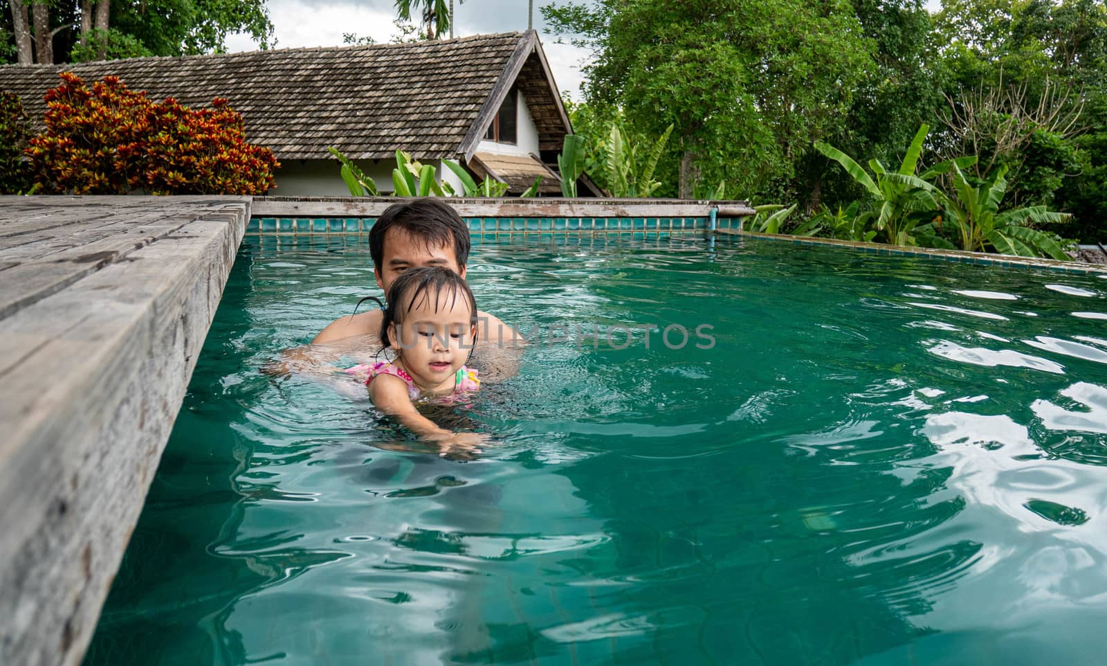 Portrait of Father and daughter enjoying a summer holiday in swimming pool at Northern resort of Thailand.