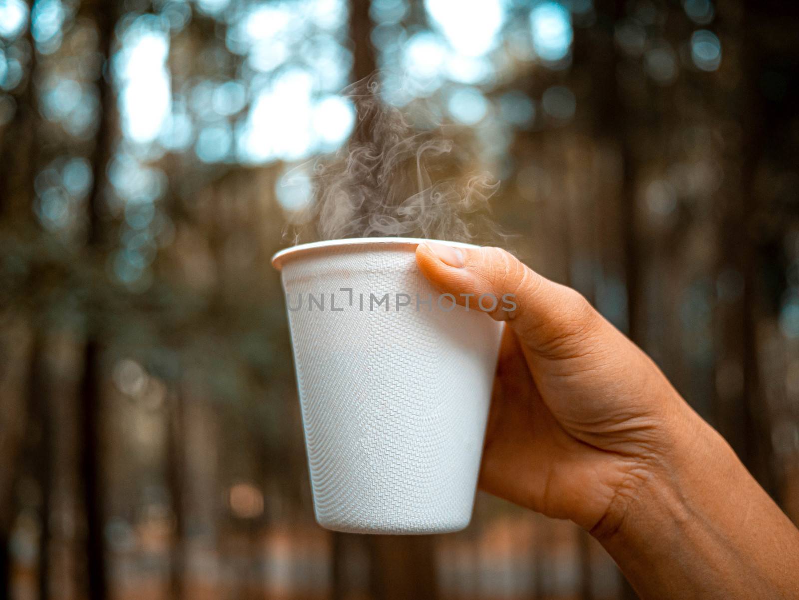 Close-up of hand holding hot beverage in paper glass in the morn by TEERASAK