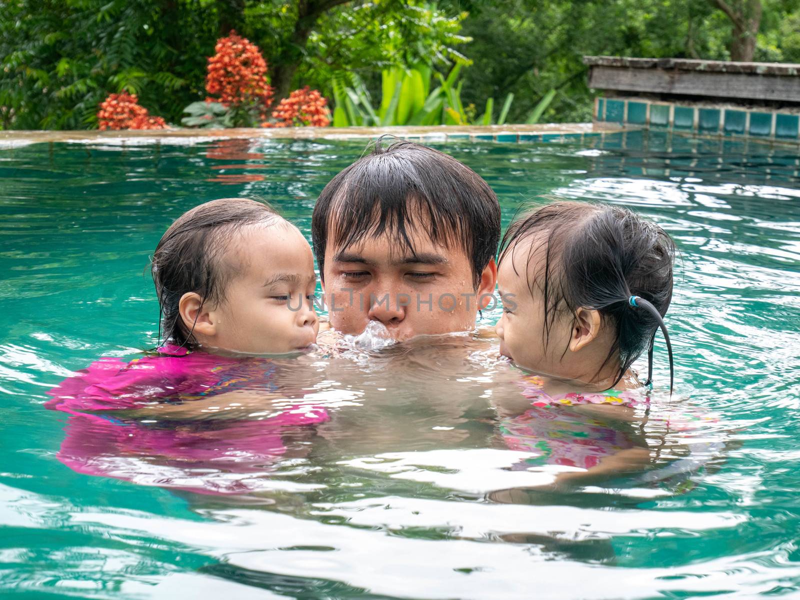 Portrait of Father and daughter enjoying a summer holiday in swimming pool at Northern resort of Thailand. by TEERASAK