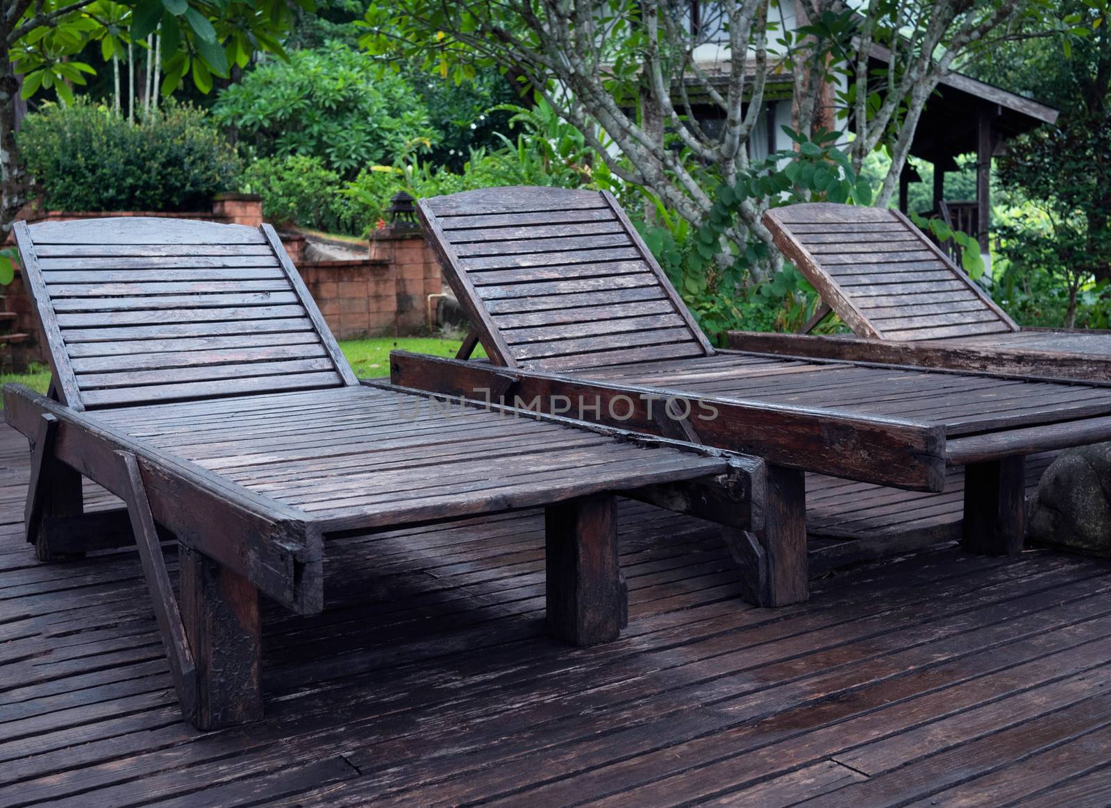 Wooden sunbed at the poolside at Northern resort of Thailand in summer day.