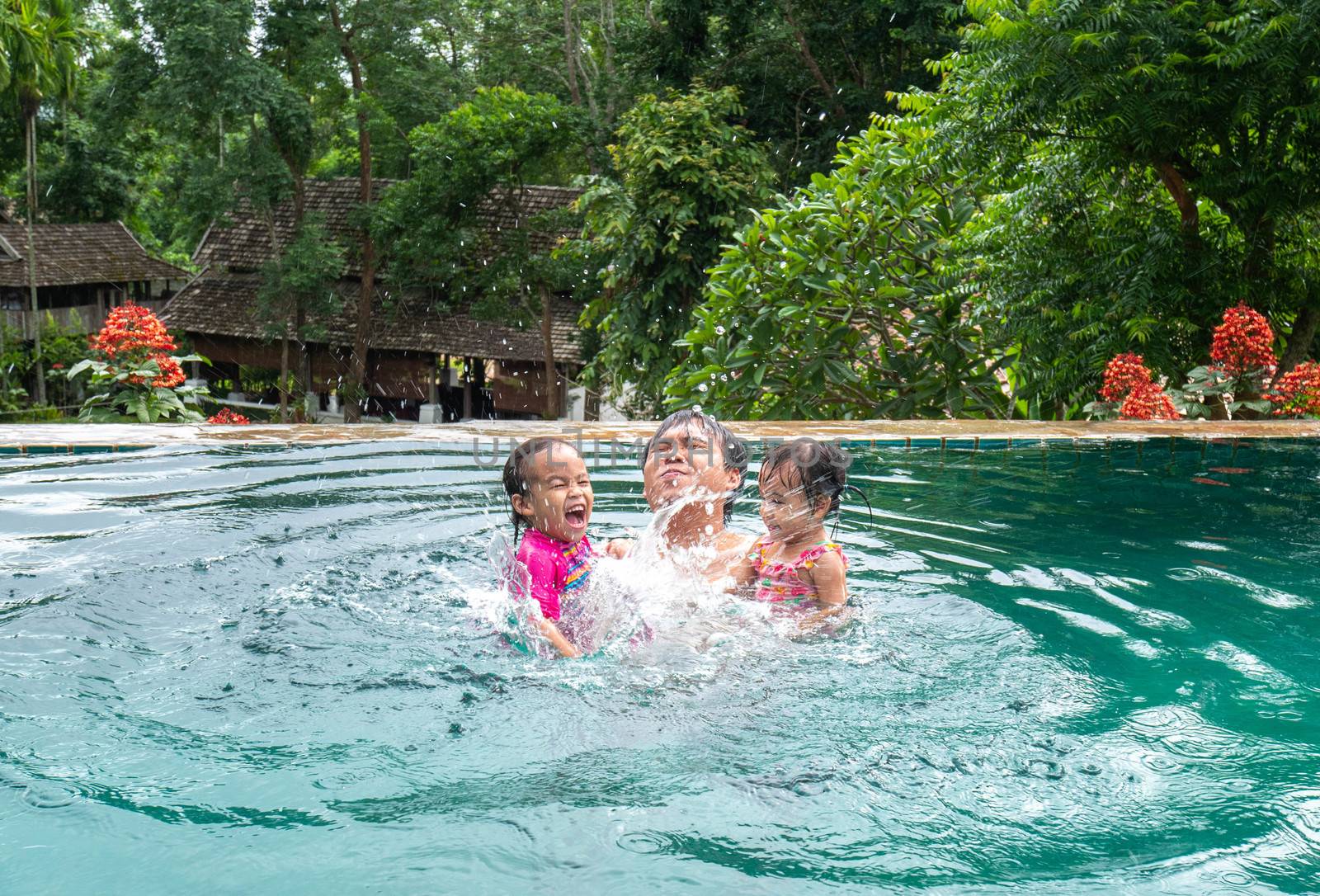 Portrait of Father and daughter enjoying a summer holiday in swimming pool at Northern resort of Thailand.