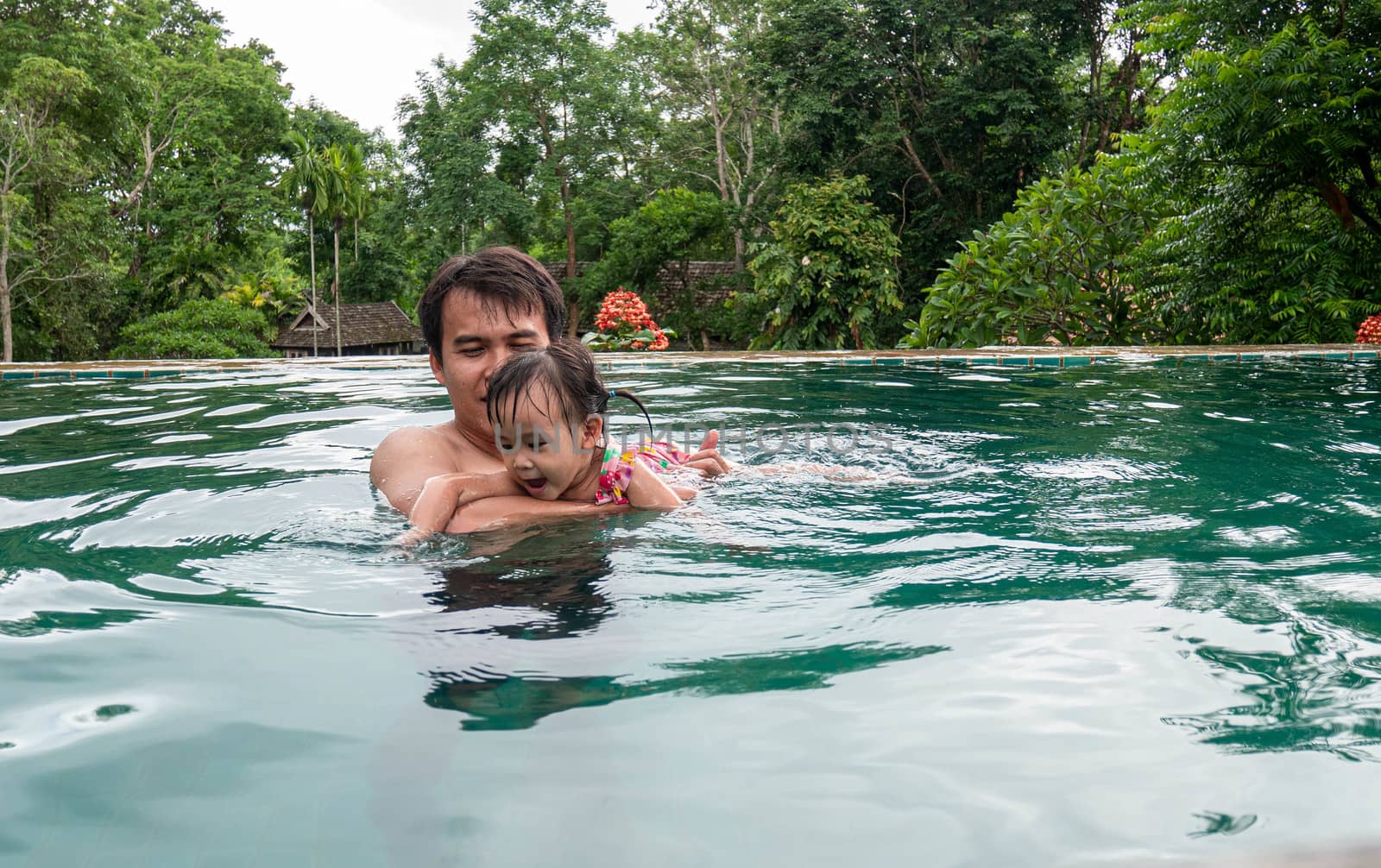 Portrait of Father and daughter enjoying a summer holiday in swimming pool at Northern resort of Thailand.