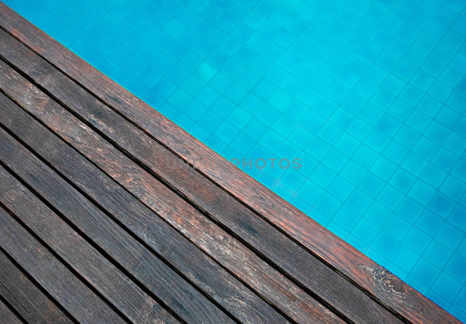 Wooden floor and wave of water in swimming pool in summer day. by TEERASAK