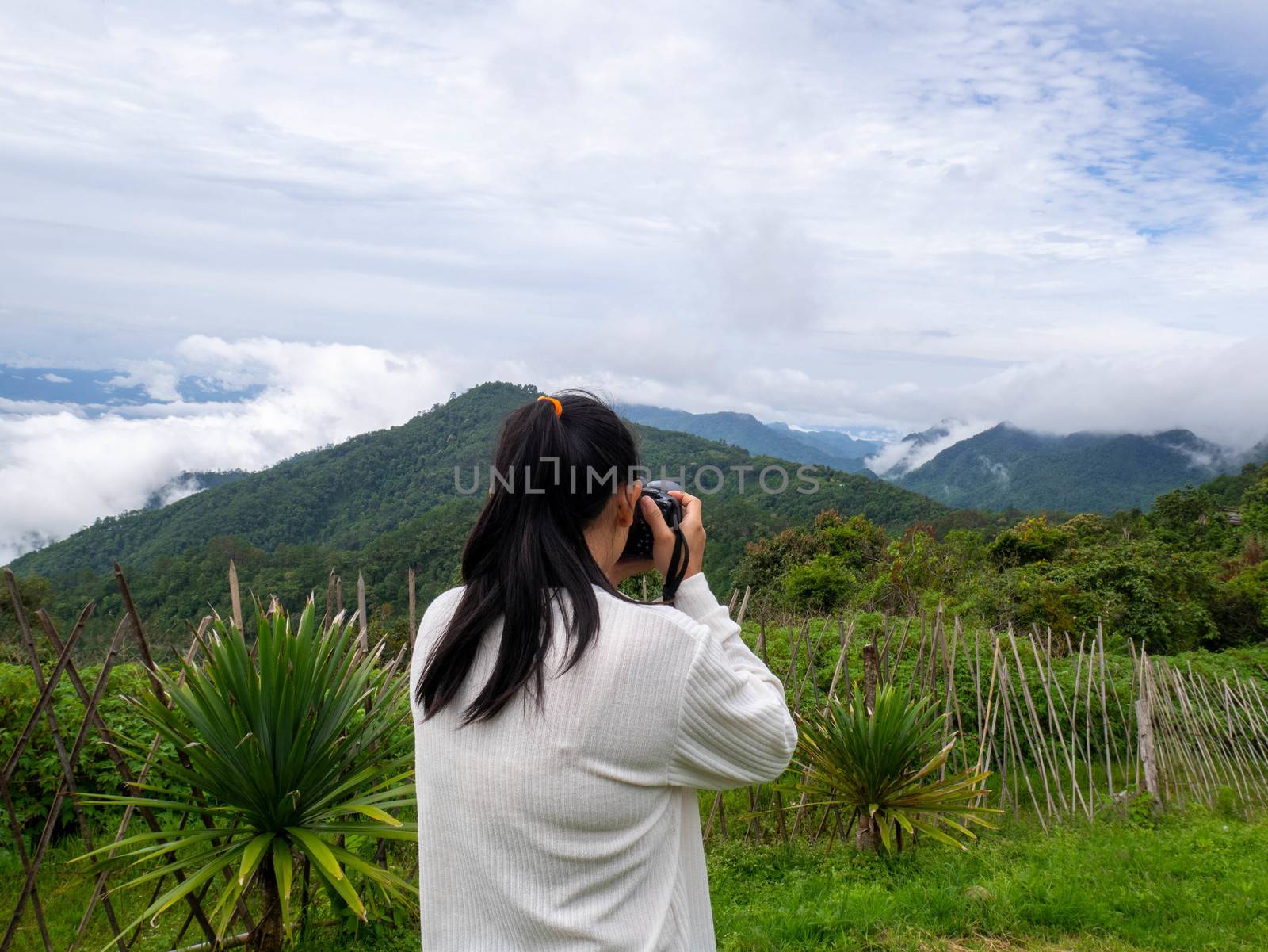 Rear of Asian woman taking pictures mountain scenery at Ang Khan by TEERASAK