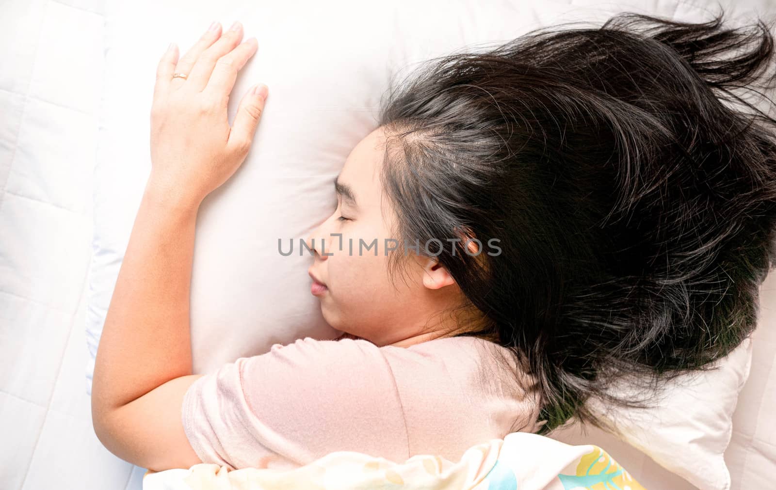 Top view of attractive Asian young woman sleeping well in bed hugging soft white pillow. Health care concept.
