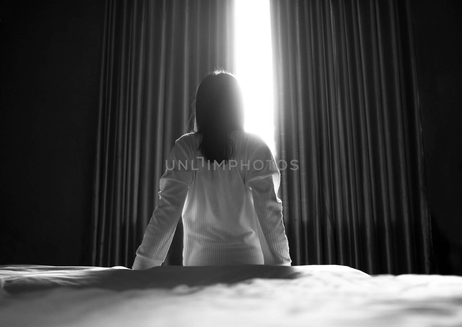 Rear of an Asian woman sitting and stretch lazily in the bright morning in bedroom. Health care concept. by TEERASAK