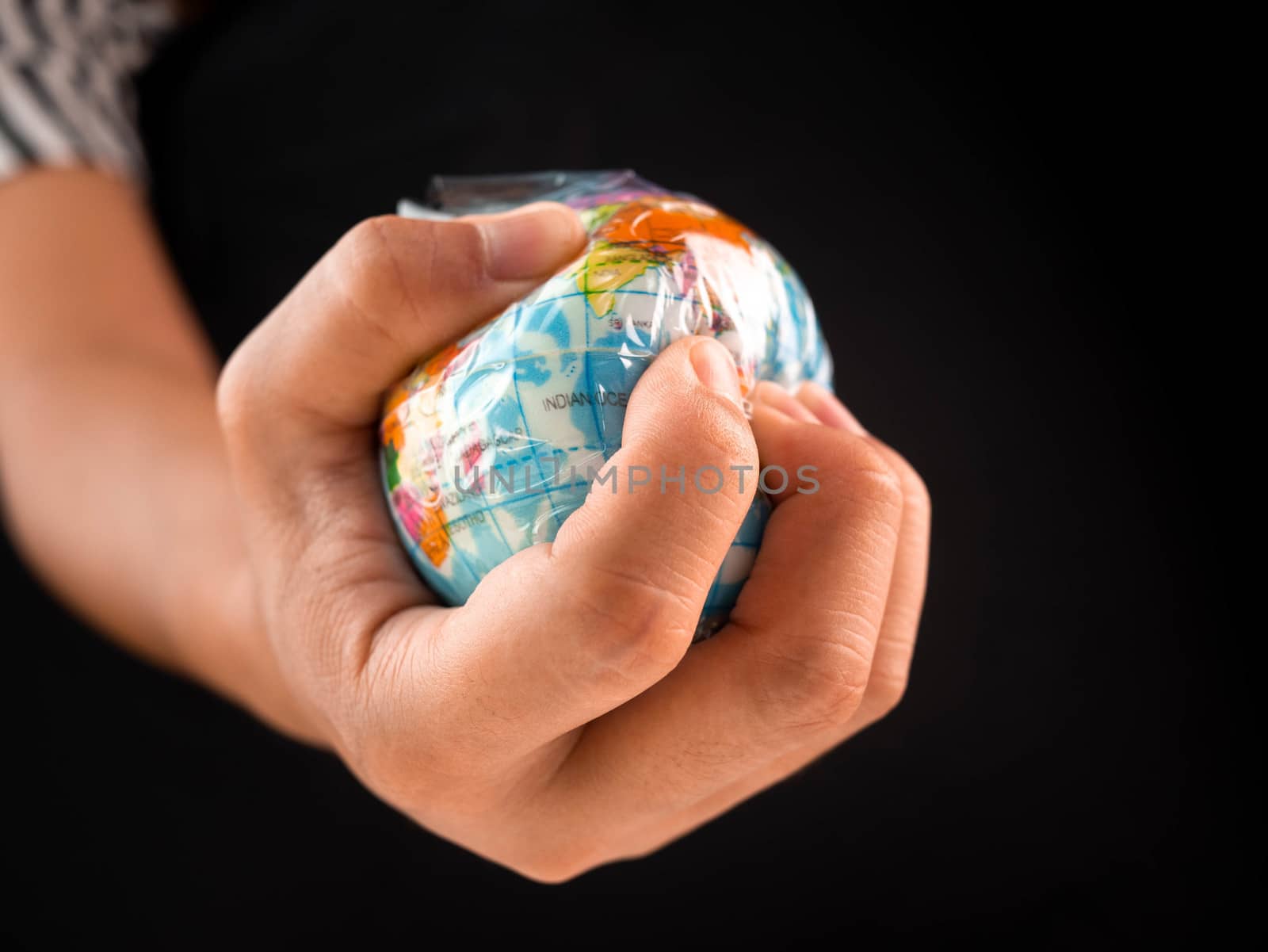 Woman hand holds the earth in plastic bag on black background. Global warming due to pollution by plastic debris. The concept of Earth Day.