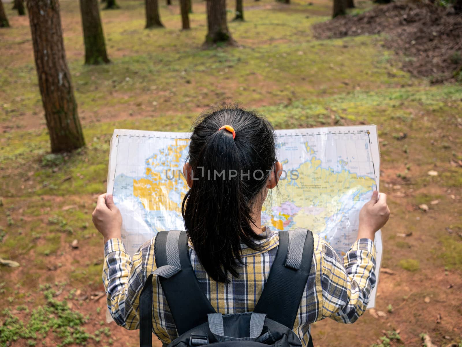 Young woman traveler with map and backpack relaxing outdoor at nature trail on summer vacations day. Lifestyle hiking concept. by TEERASAK