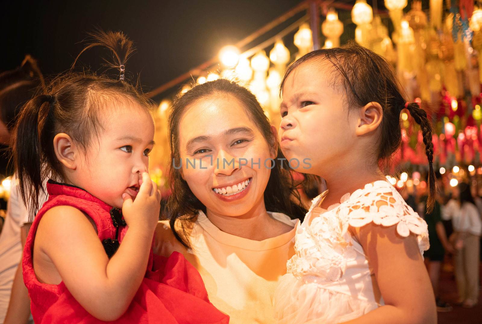 Happy Asian family standing over light from Thai lanna lanterns background at night in Yi Peng Festival.