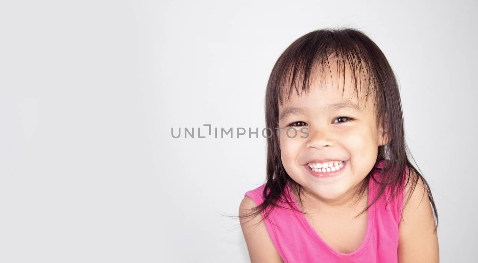 Happy Asian child girl wearing pink dress isolated on white background.