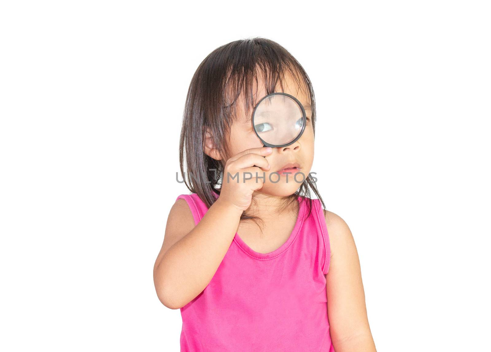 Adorable Asian child holding a magnifying glass and wearing pink dress isolated on a white background.