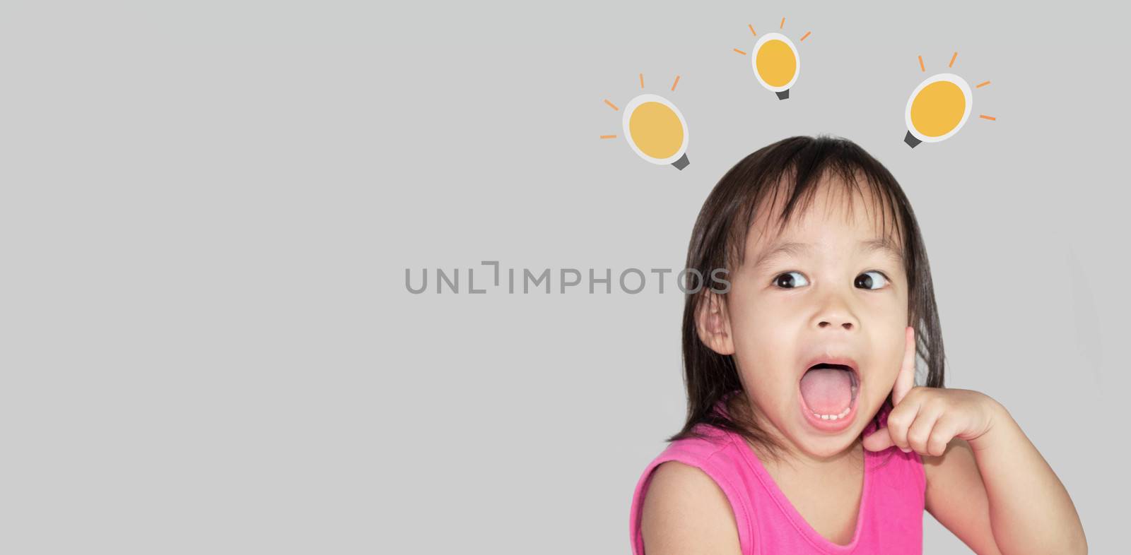 Adorable Asian child thinking and wearing pink dress isolated on a grey background. by TEERASAK