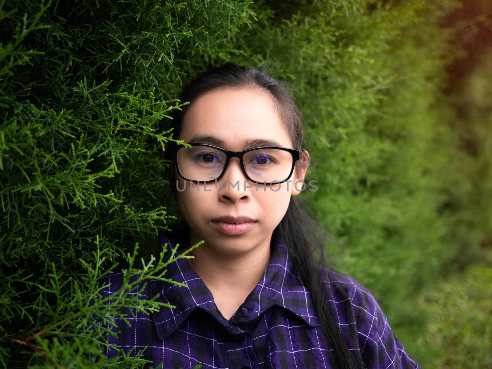 Portrait of young confident woman against background of summer green park.