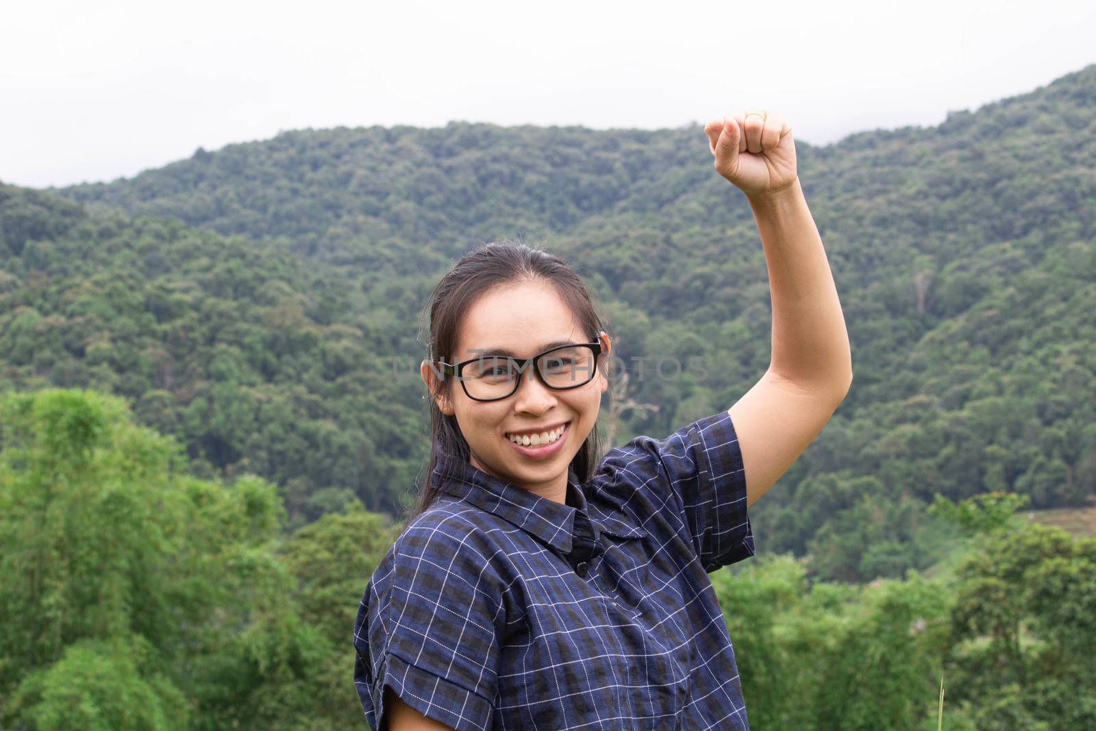 Asian young woman smile and raising her arms with a look of success on nature background.