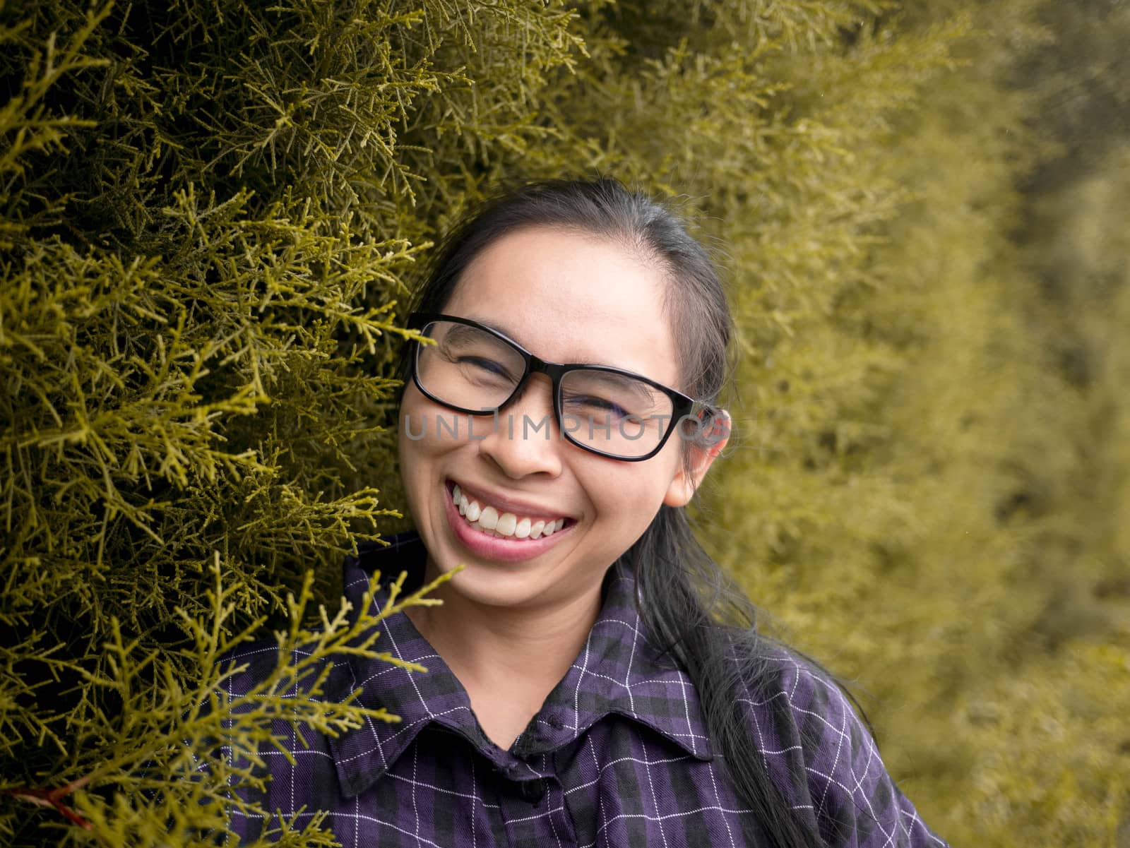 Portrait of young happy smiling woman against background of summer park.