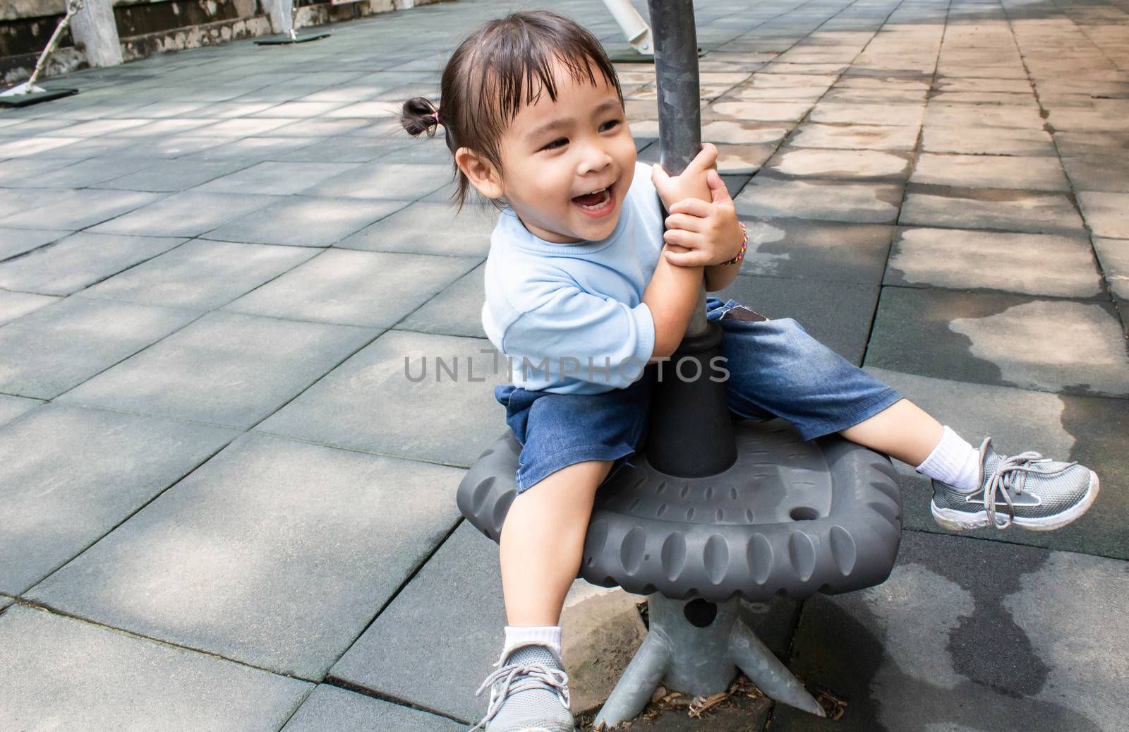 Happy asian little child girl having fun to play in the playground in summer time.