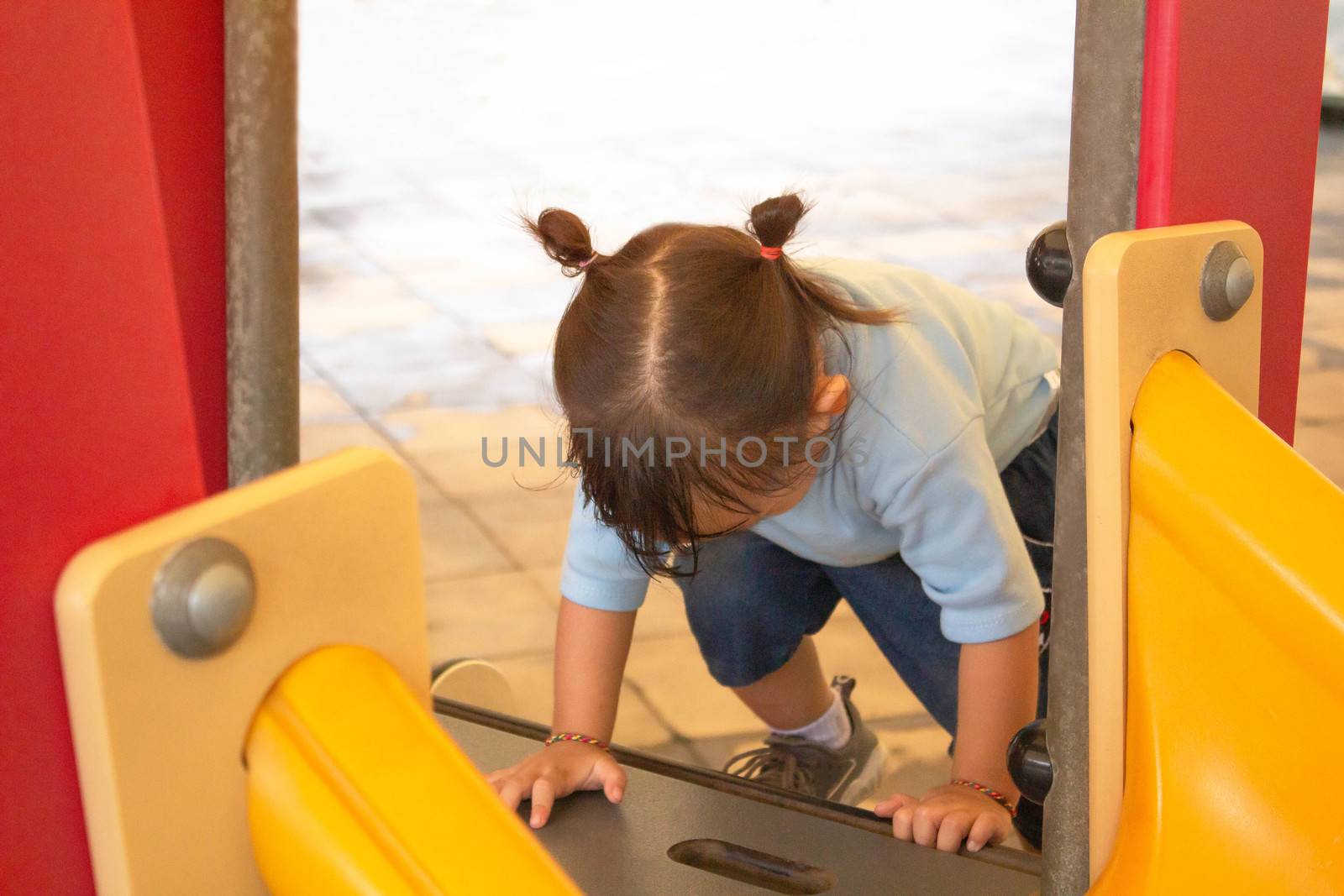 Asian little child girl having fun on a playground outdoors in summer.