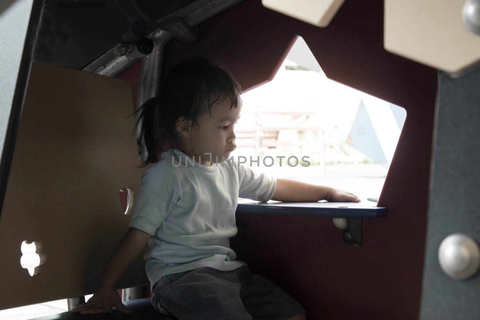 Asian little child girl sitting to rest in small plastic house in the playground.