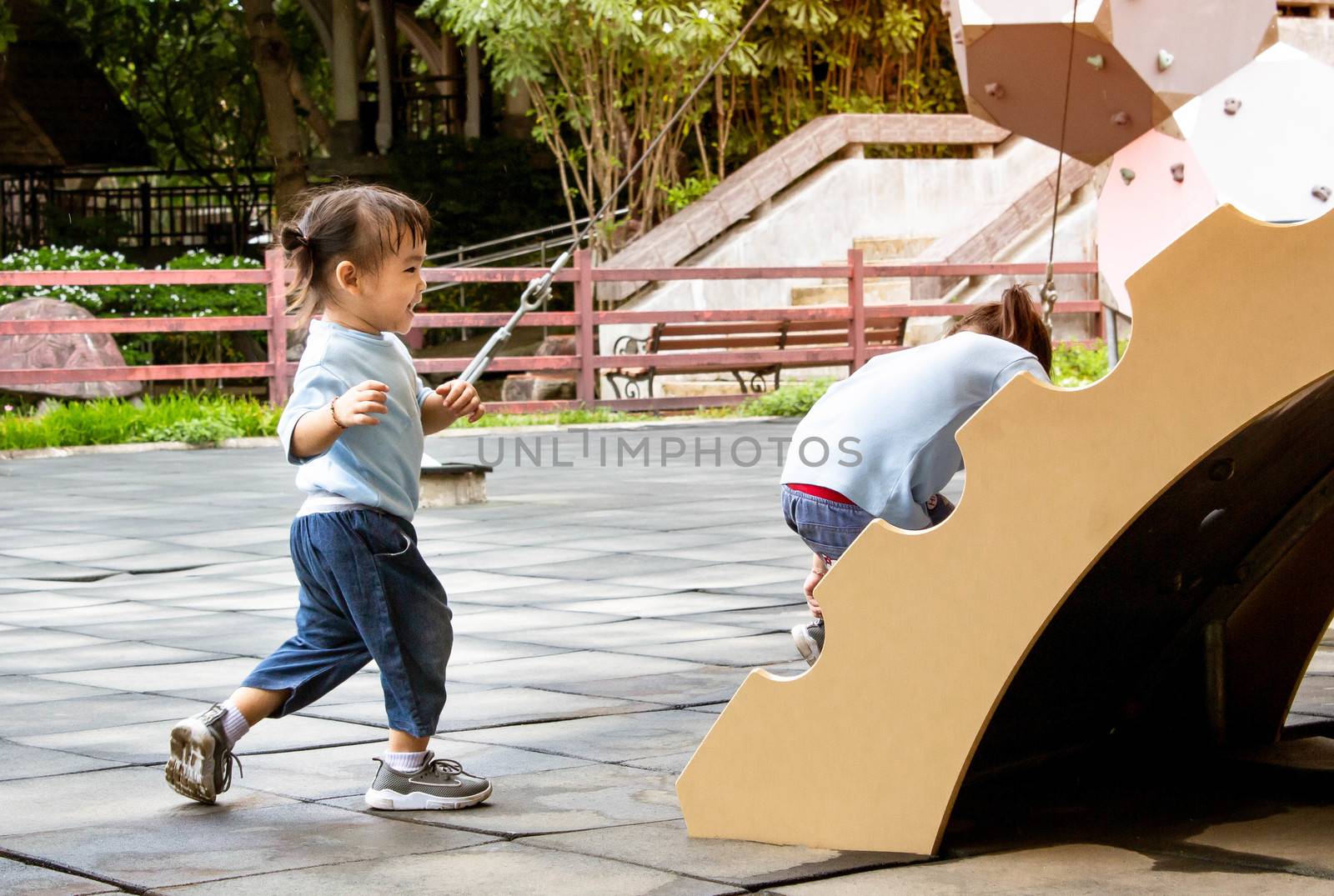 Asian little child girl having fun on a playground outdoors in summer.