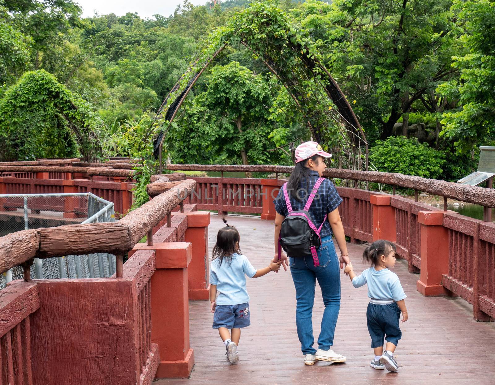 24 August 2019- Chiang Mai,Thailand ; Happy Asian family holding hands and walking together on the bridge to look animals in the Night safari. by TEERASAK