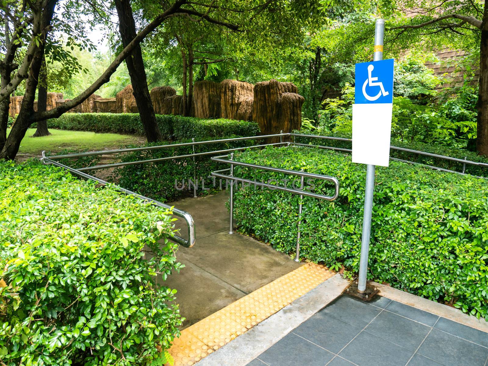 Concrete ramp way with stainless steel handrail and disabled sig by TEERASAK