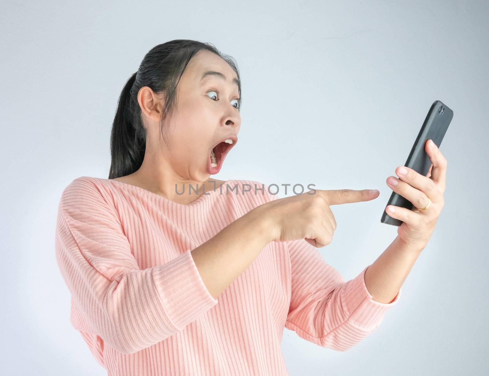 Asian woman shocked what she see in the smartphone and pointing it, Isolated on white background.