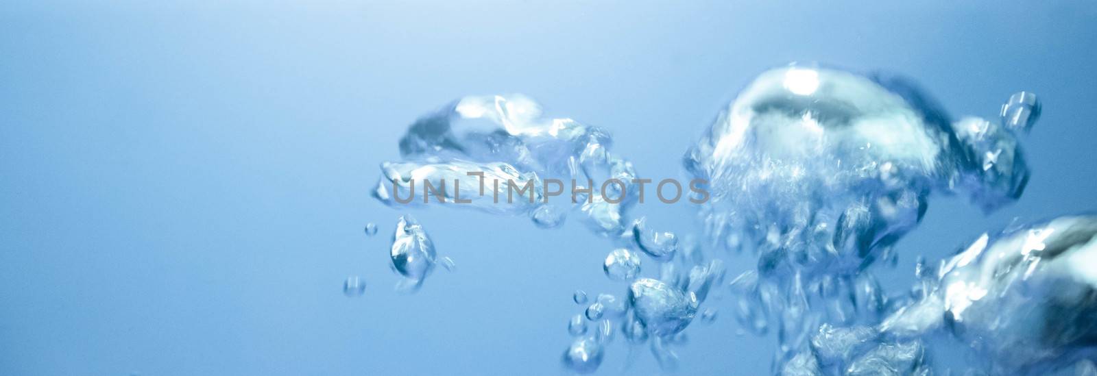 Air bubbles rising up to surface in blue pure water. Abstract background.