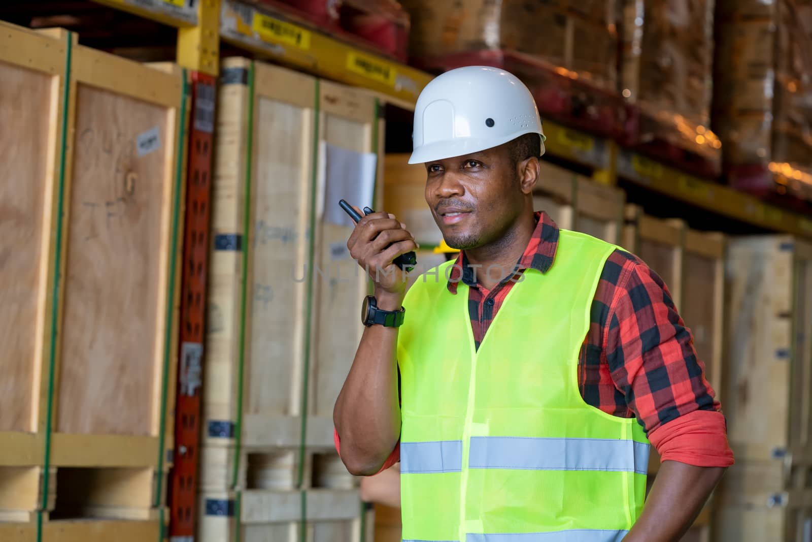 Warehouse worker using handheld radio receiver for communication in a large warehouse.