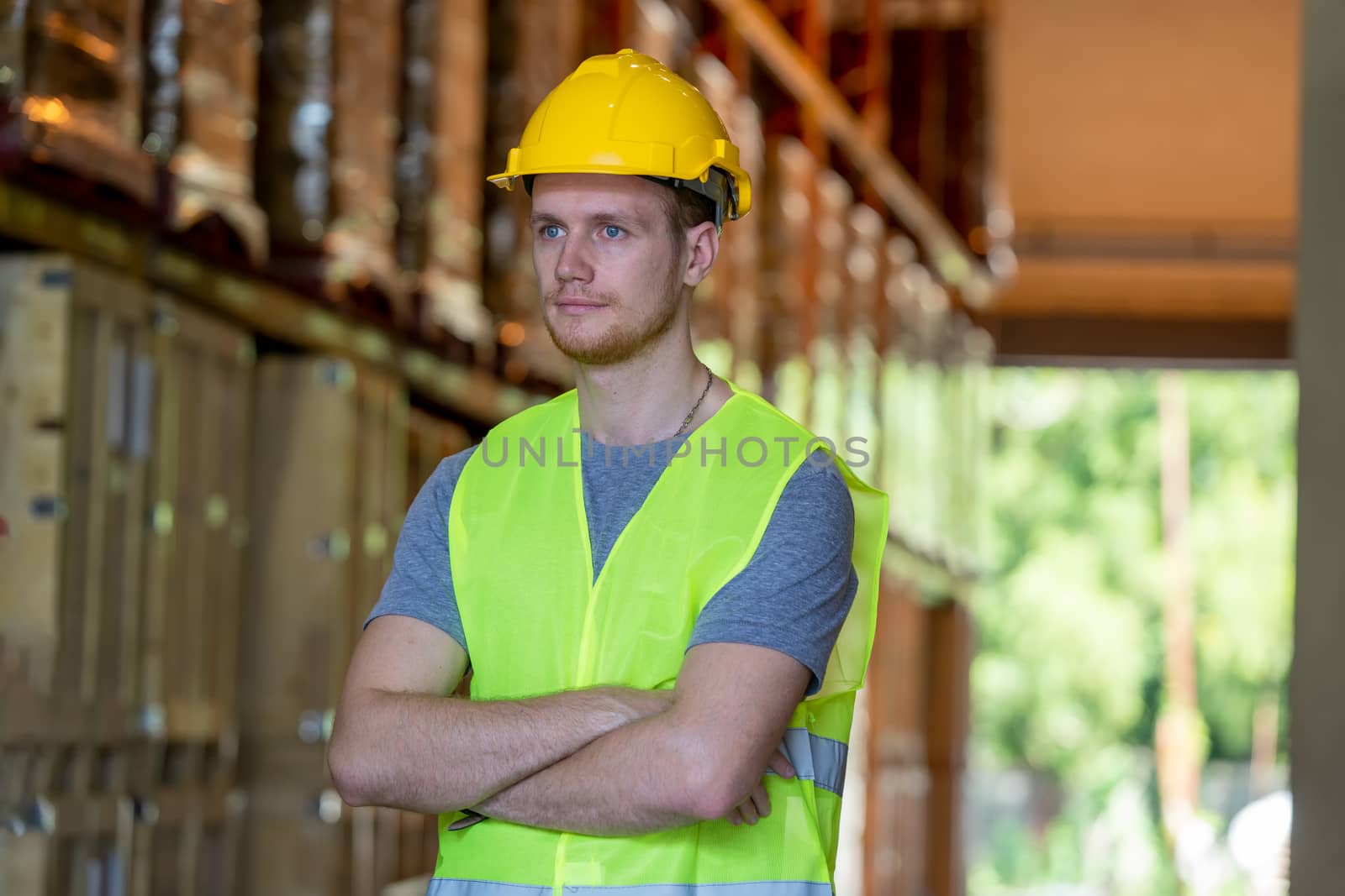 Portrait of warehouse worker standing with arms crossed in factory.