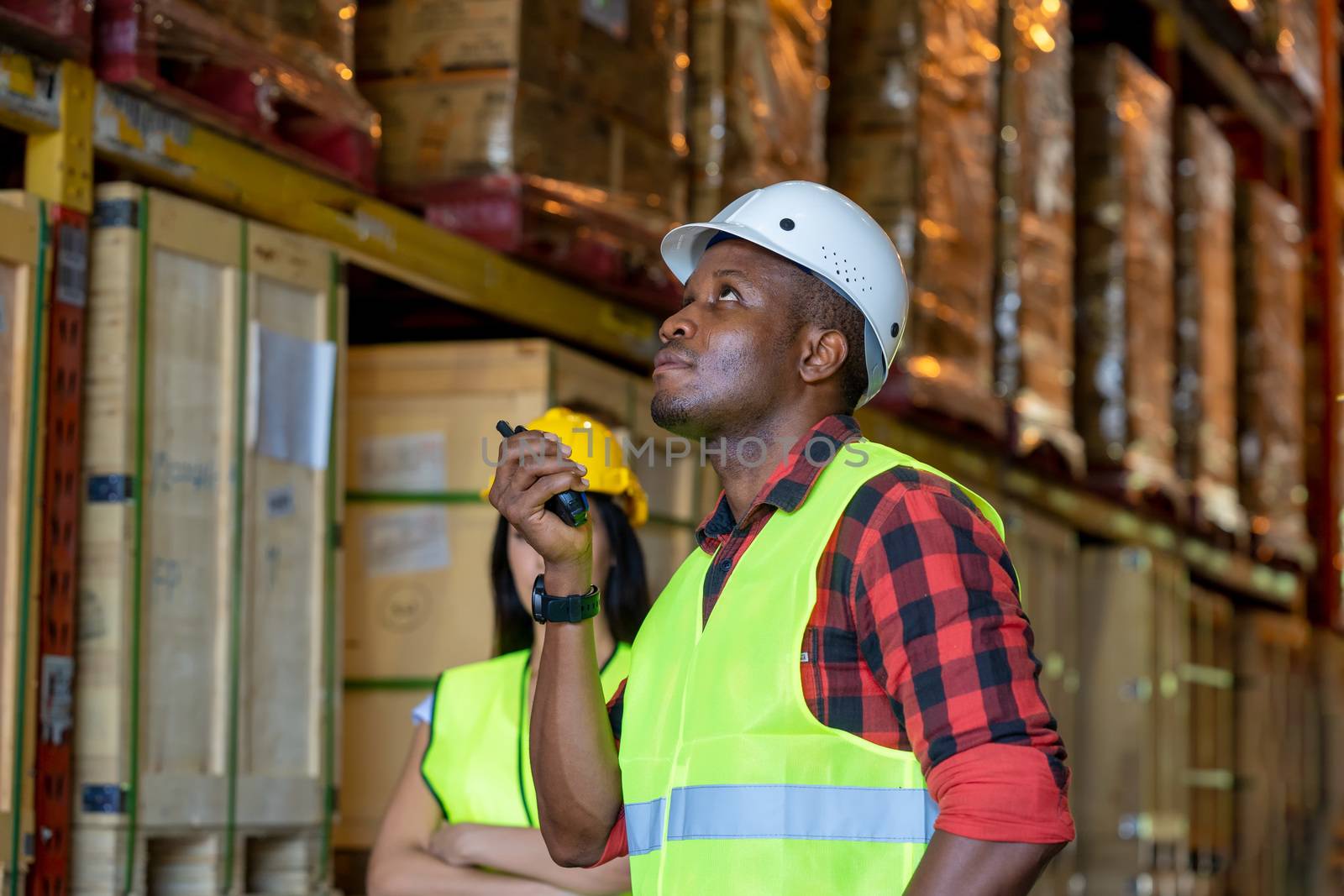 Warehouse worker using handheld radio receiver for communication in a large warehouse.